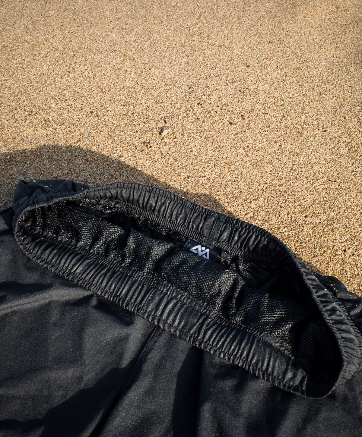 Inner woven label and mesh lining of black swim shorts