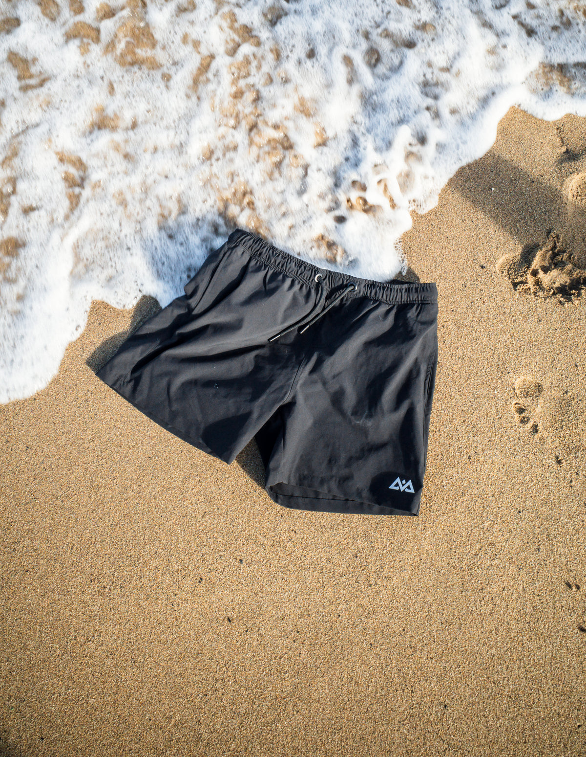 Black drawstring swim shorts at water's edge
