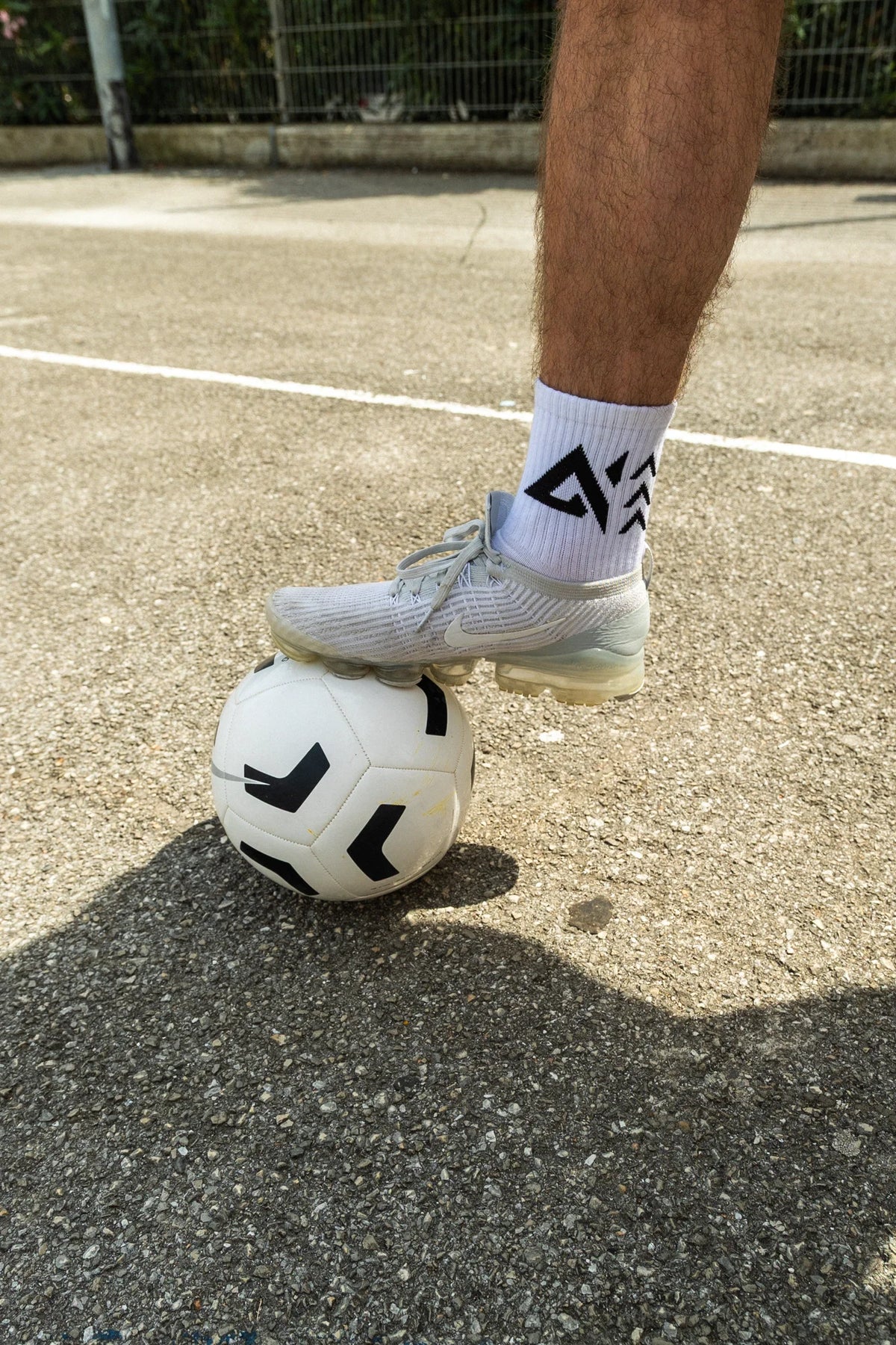 White crew socks with black geometric logo worn with athletic sneaker on sports court