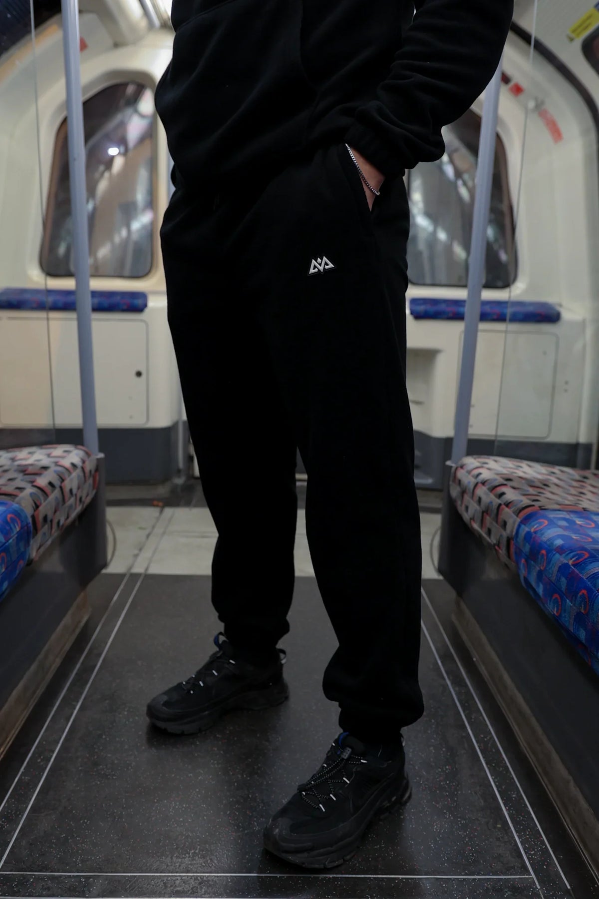 Black fleece joggers with logo on thigh worn in subway