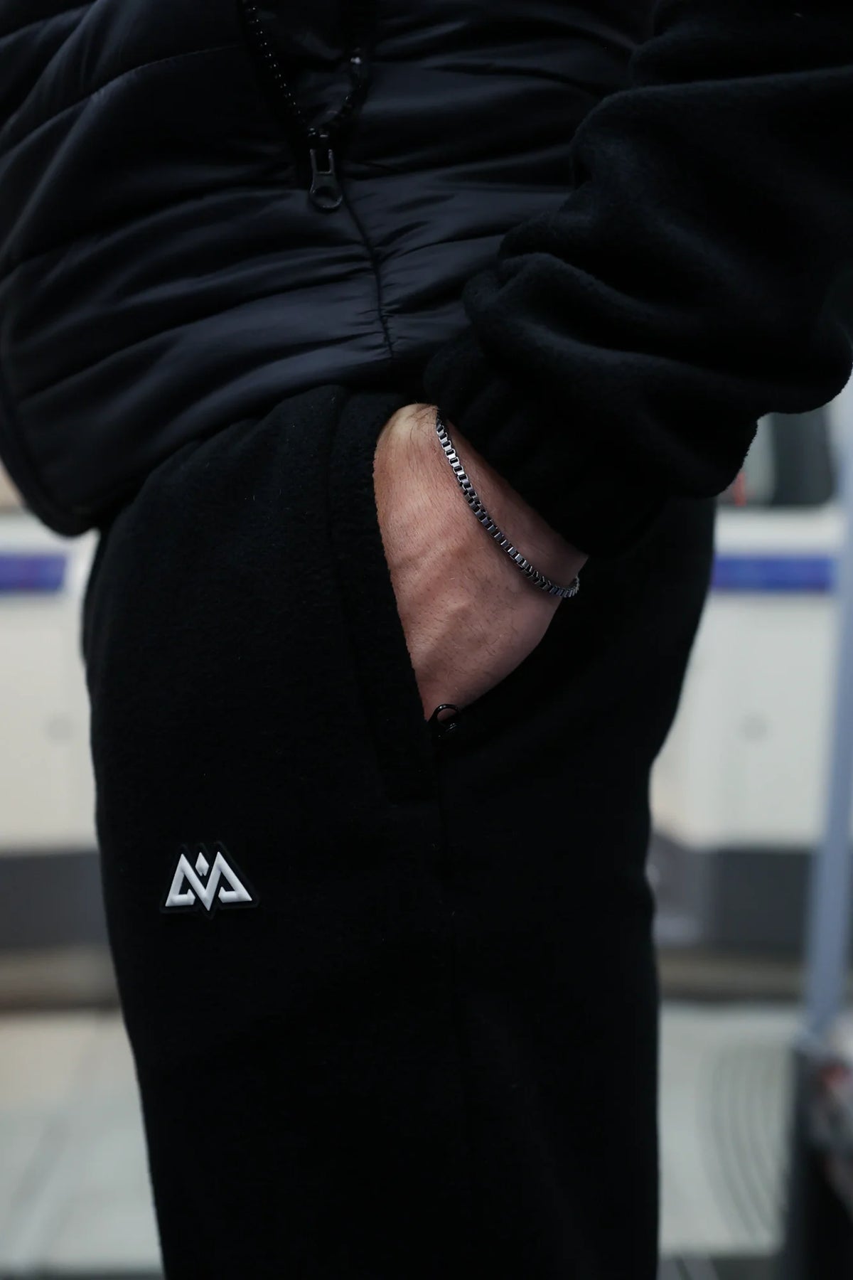 Detail of side pocket and logo patch on black joggers