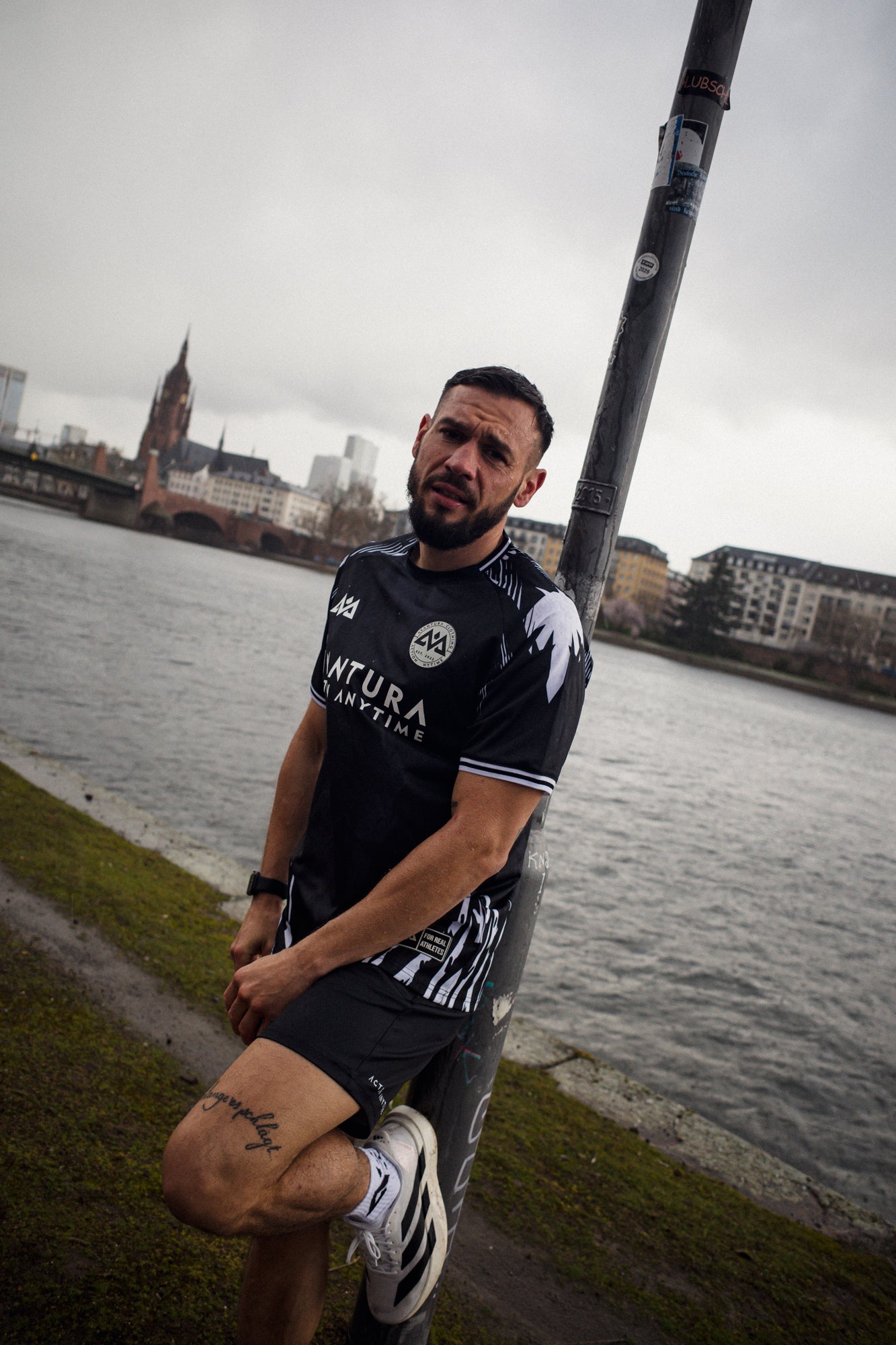 Model wearing black jersey with circular emblem and hem label