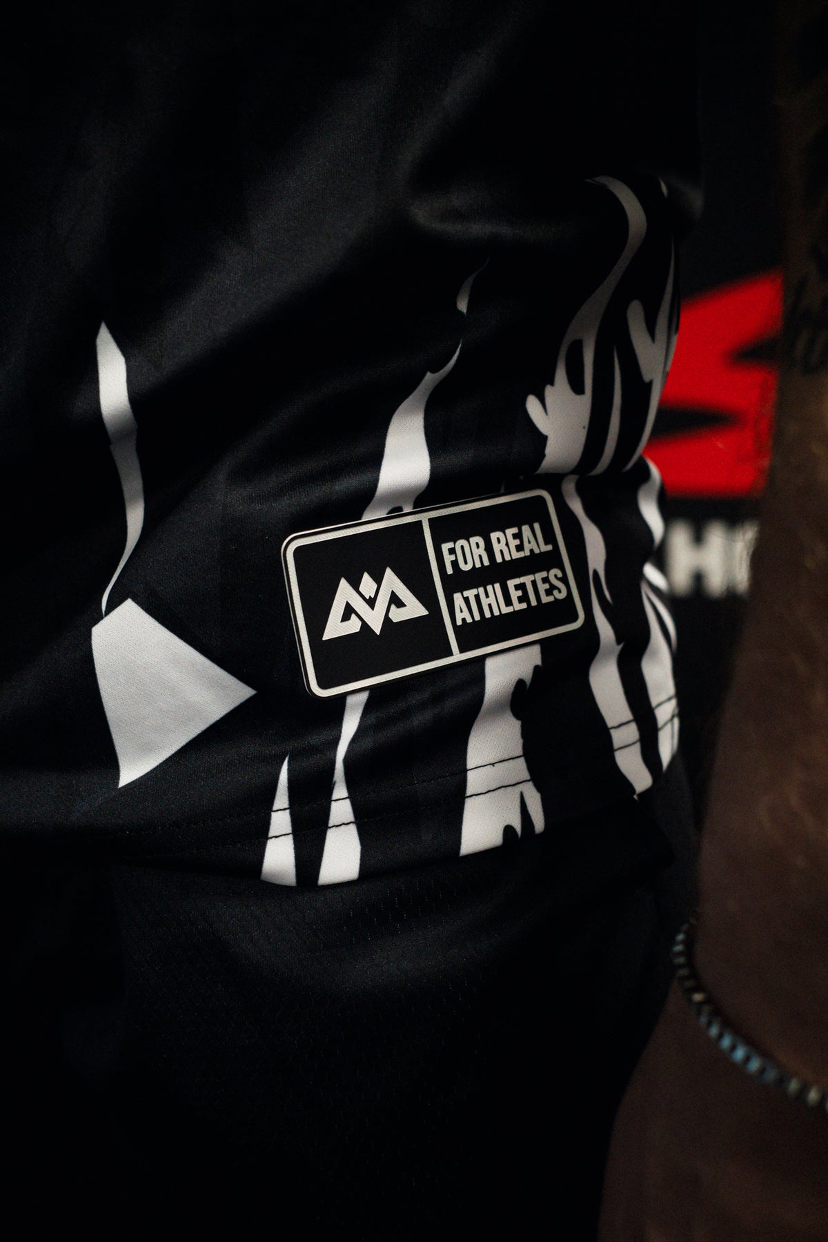 Side hem detail of black jersey with silicone patch logo