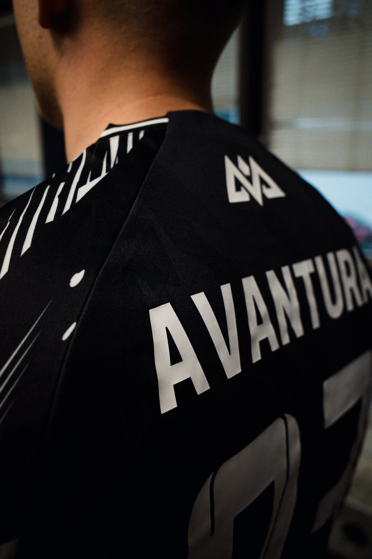 Upper back detail of black jersey with AVANTURA text and logo