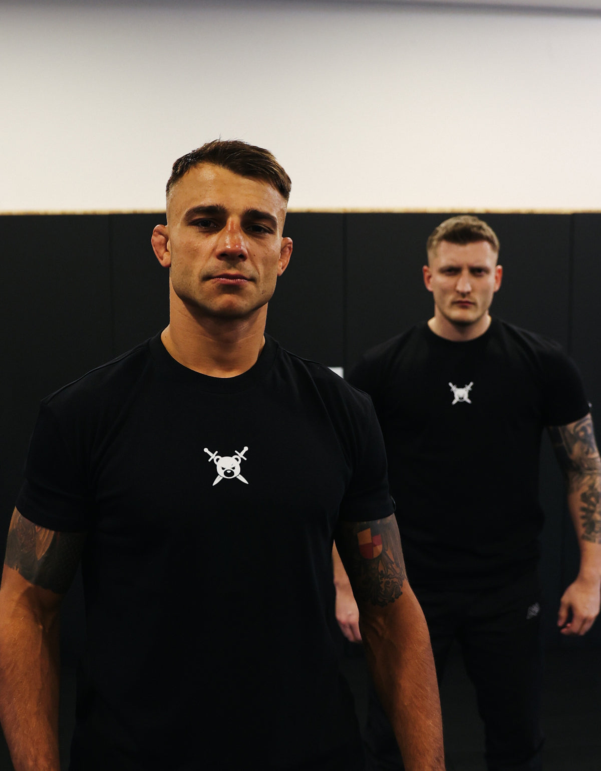 Schwarzes AVANTURA T-Shirt mit Logo getragen von tätowiertem Mann