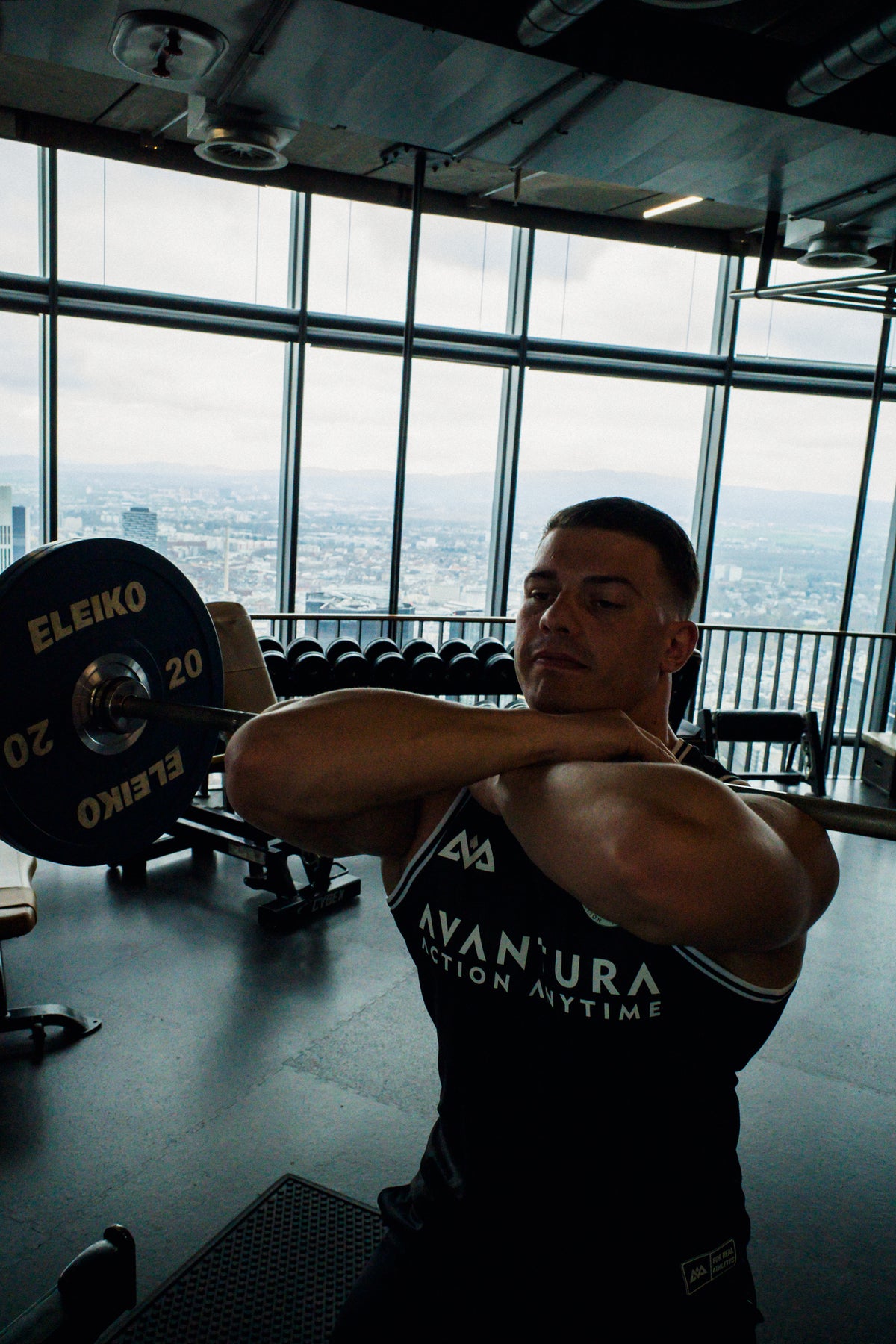 Athlete squatting in black Avantura tank top with white lettering