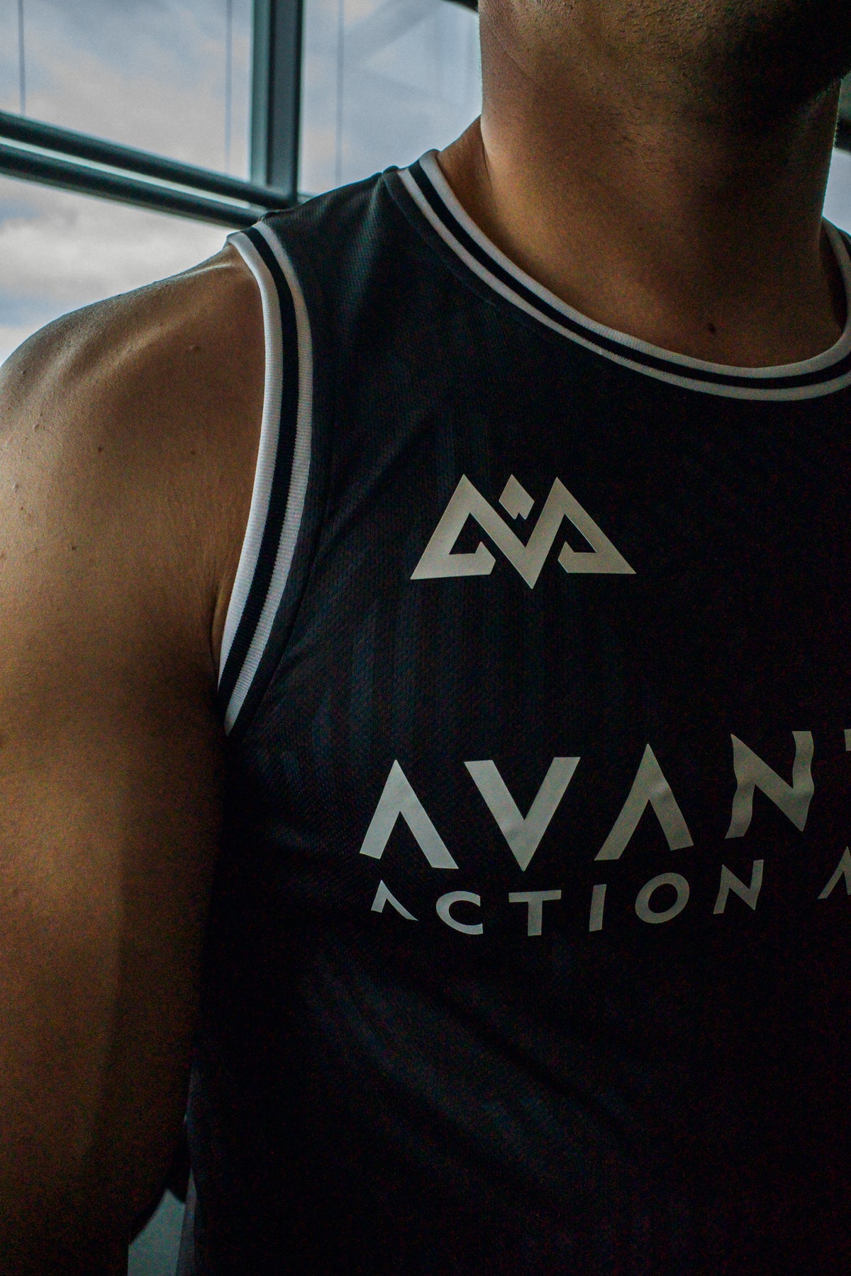 Close-up of ribbed neckline and geometric logo on black Avantura tank top