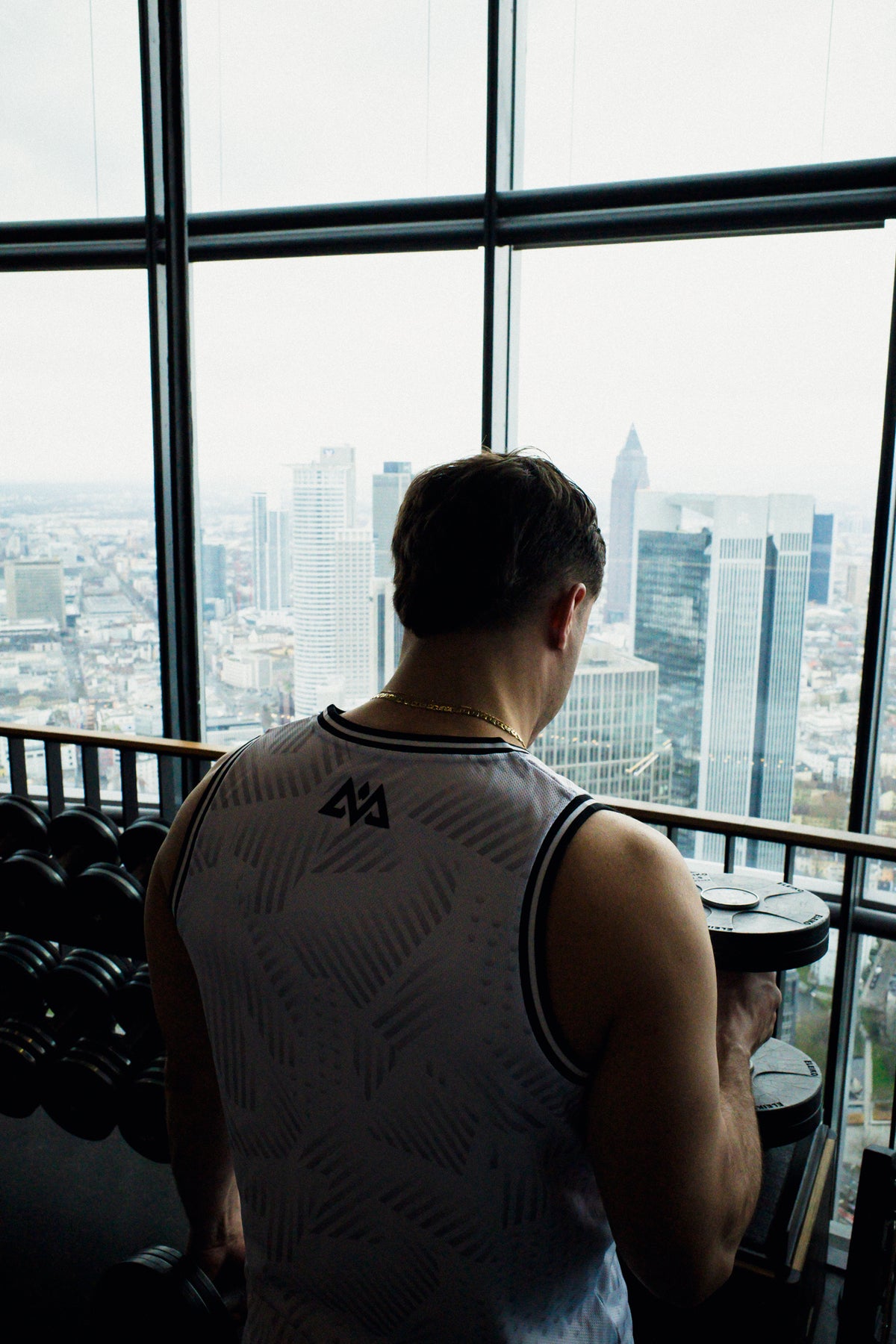 Back view of white sleeveless gym tank top showing geometric logo and fit