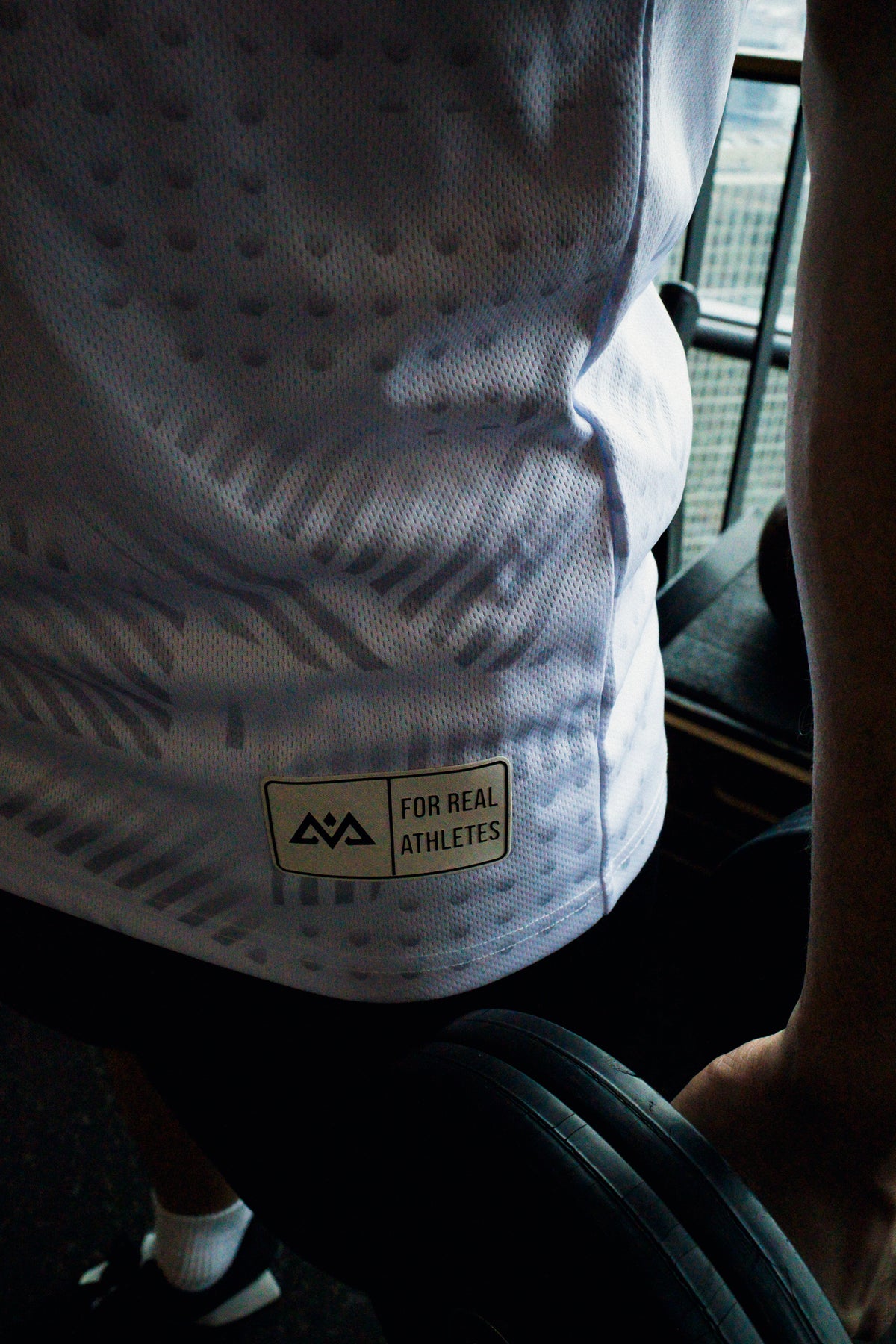 Detail shot of woven hem label reading 'For Real Athletes' on white tank