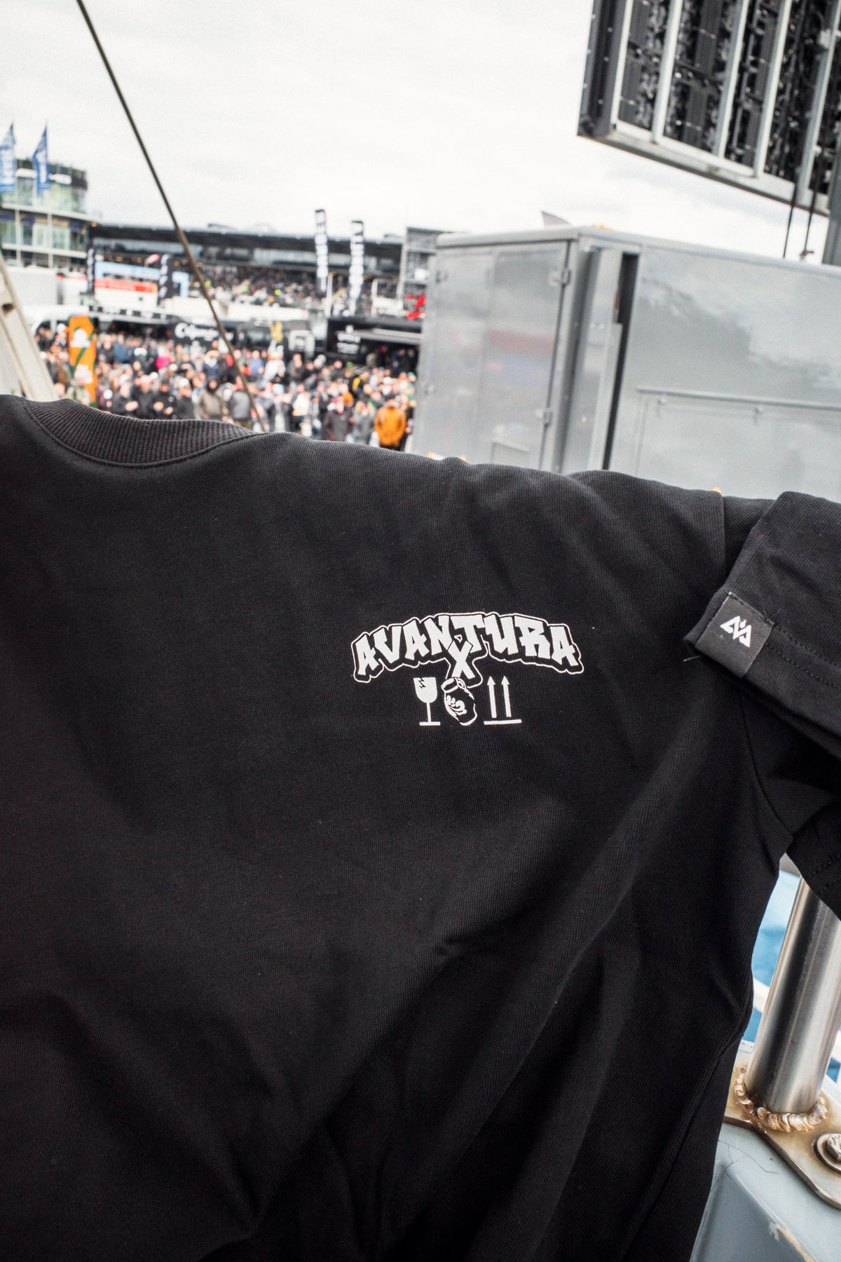 Close-up of black Avantura T-shirt left chest logo and sleeve woven label detail