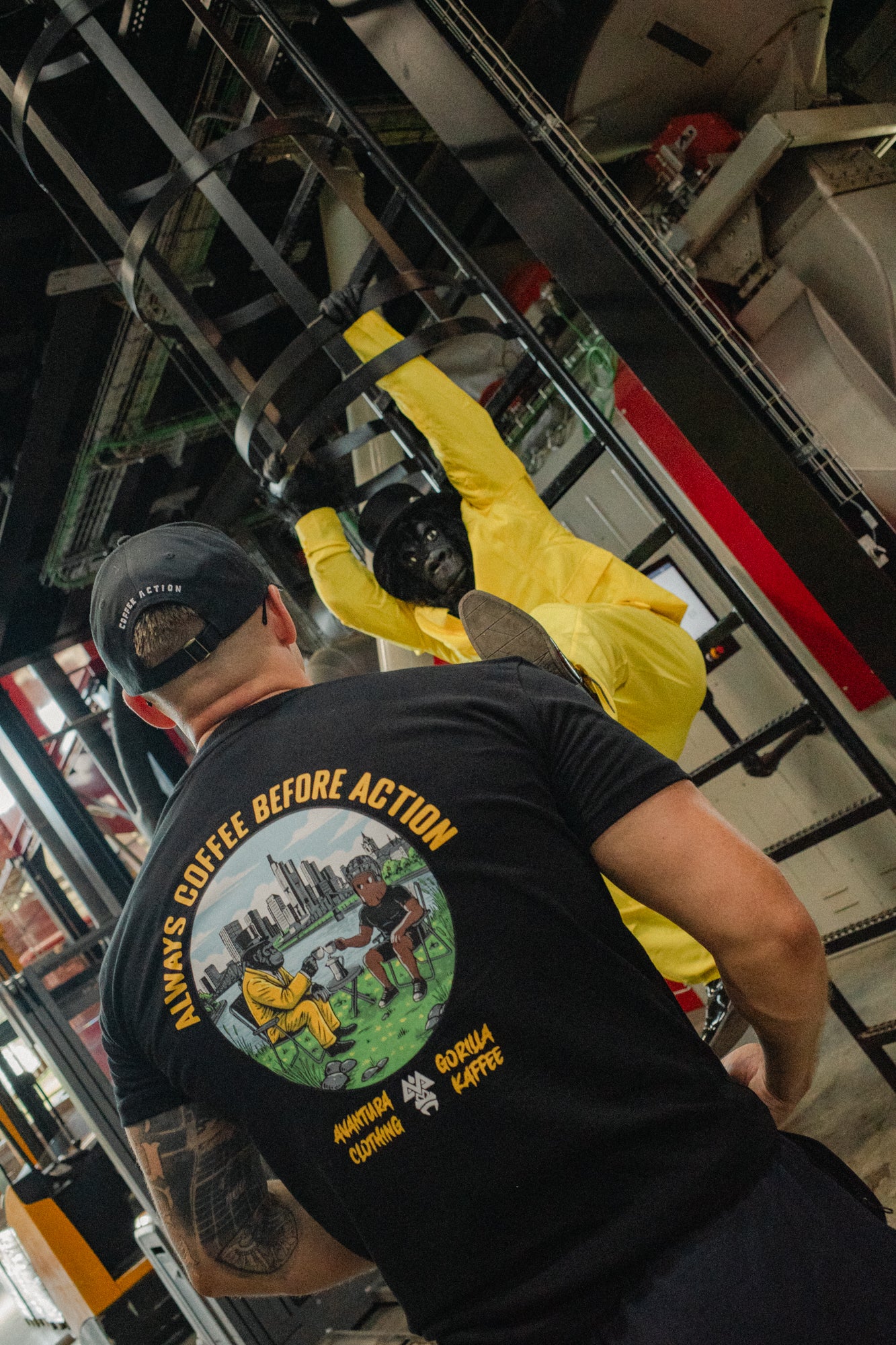 Black t-shirt back print with two gorillas at table and arched yellow slogan text