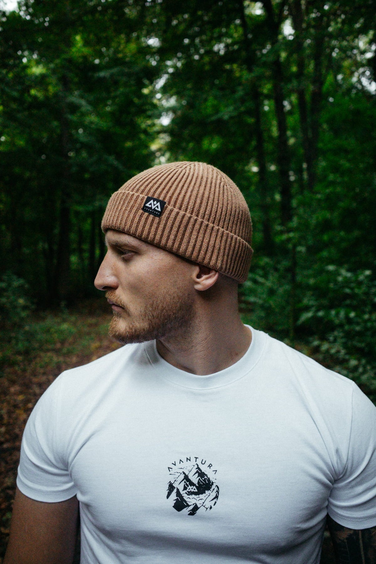 Side profile of man with folded beige beanie showing brand label