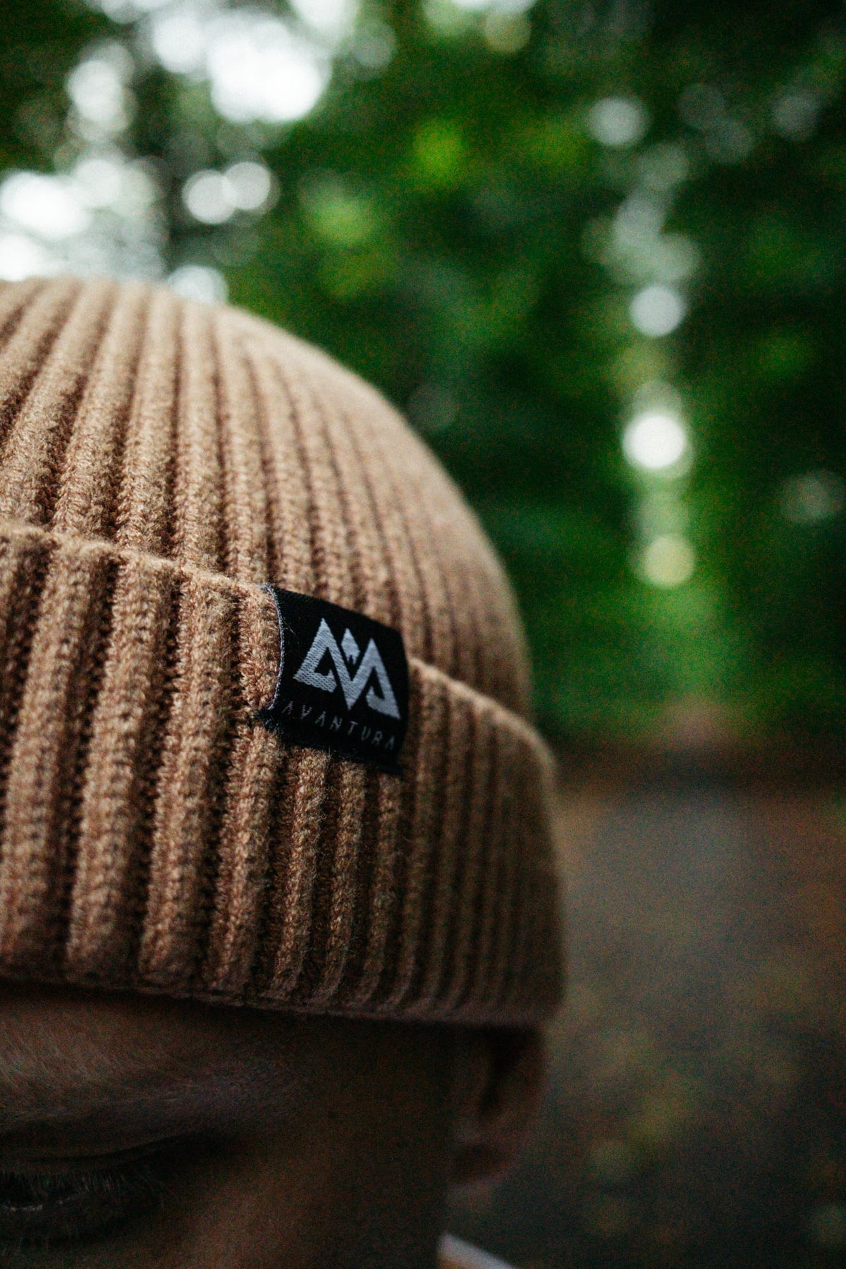 Beige ribbed knit beanie with small black logo label
