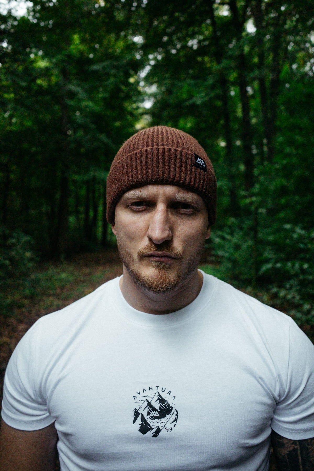 Braune gerippte Strickmütze mit kleinem Logo, getragen im Wald