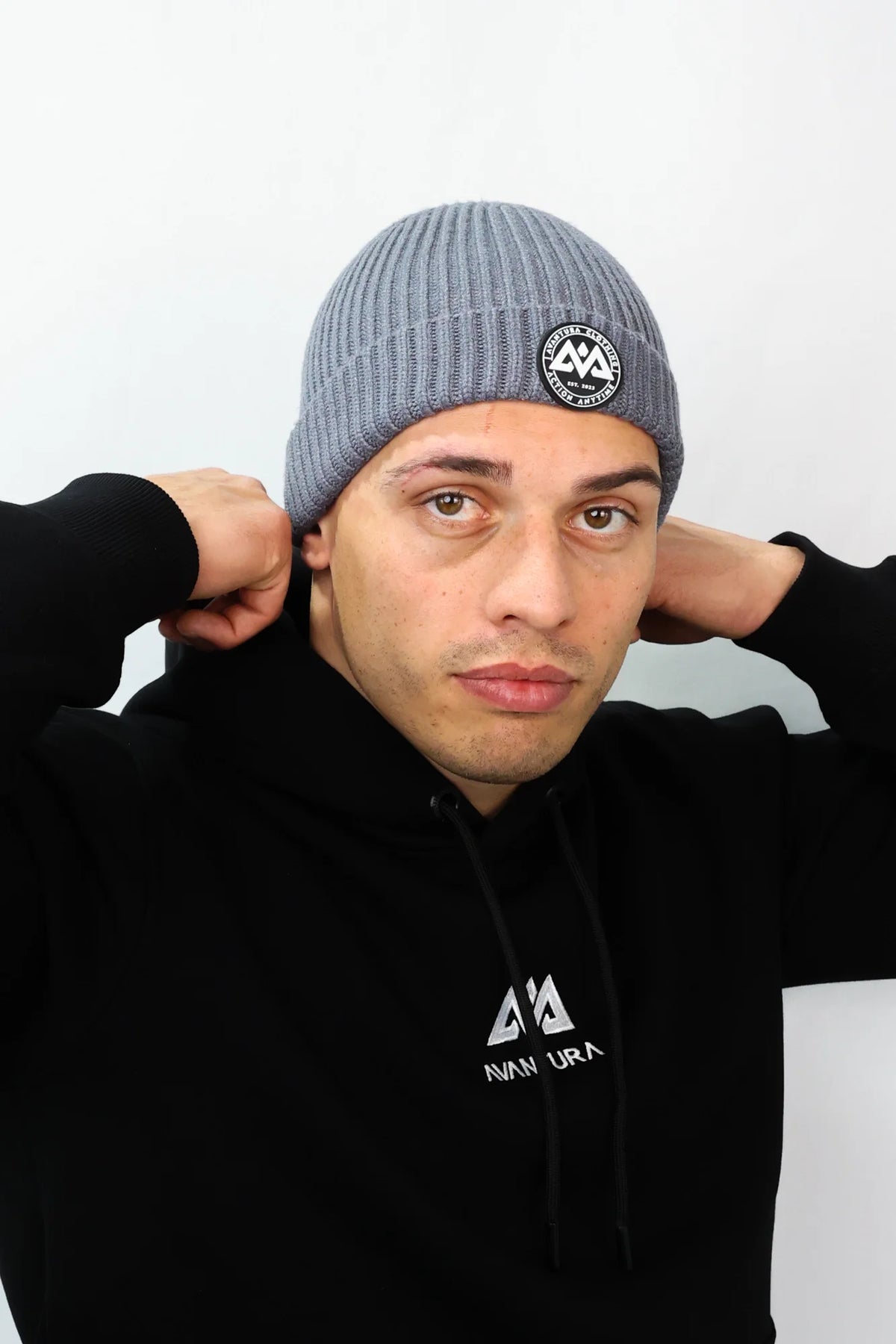 Model adjusting grey beanie with folded cuff and logo