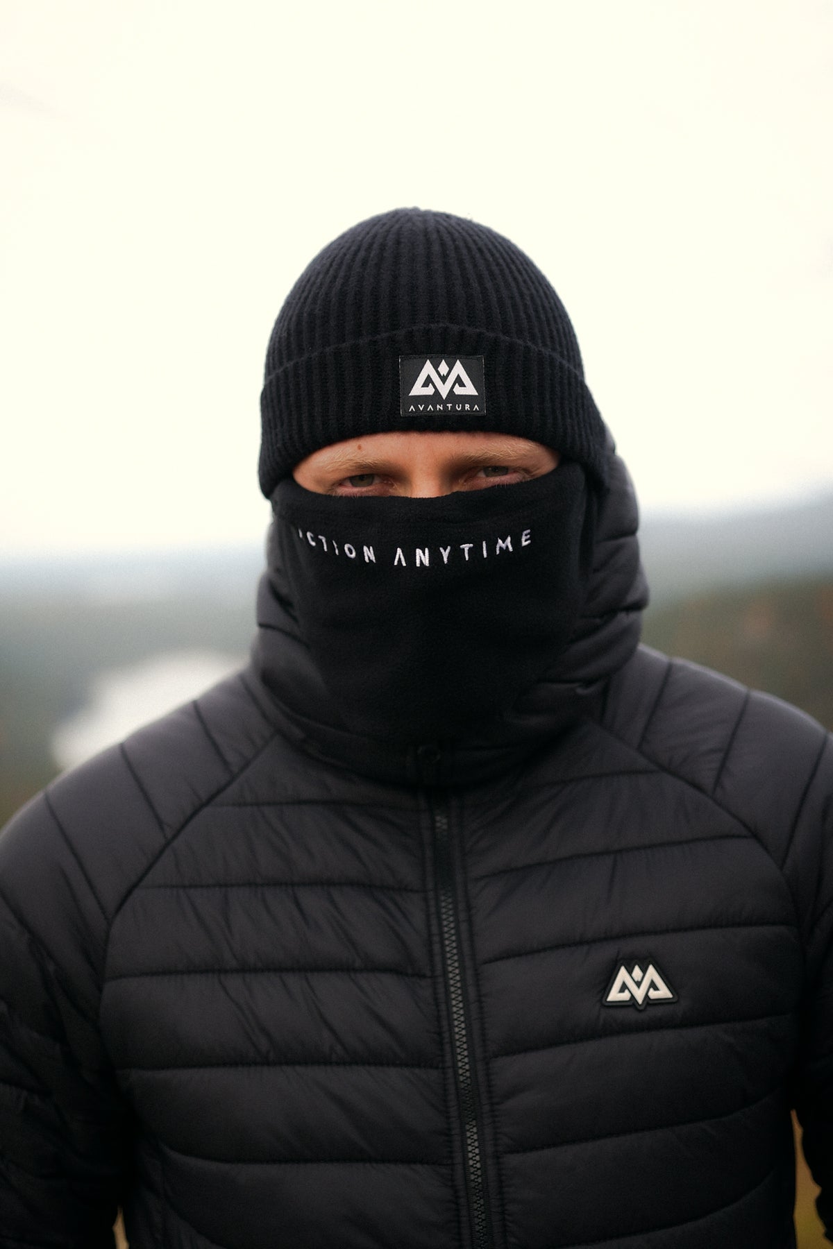 Close-up of black knit beanie featuring woven AVANTURA patch logo