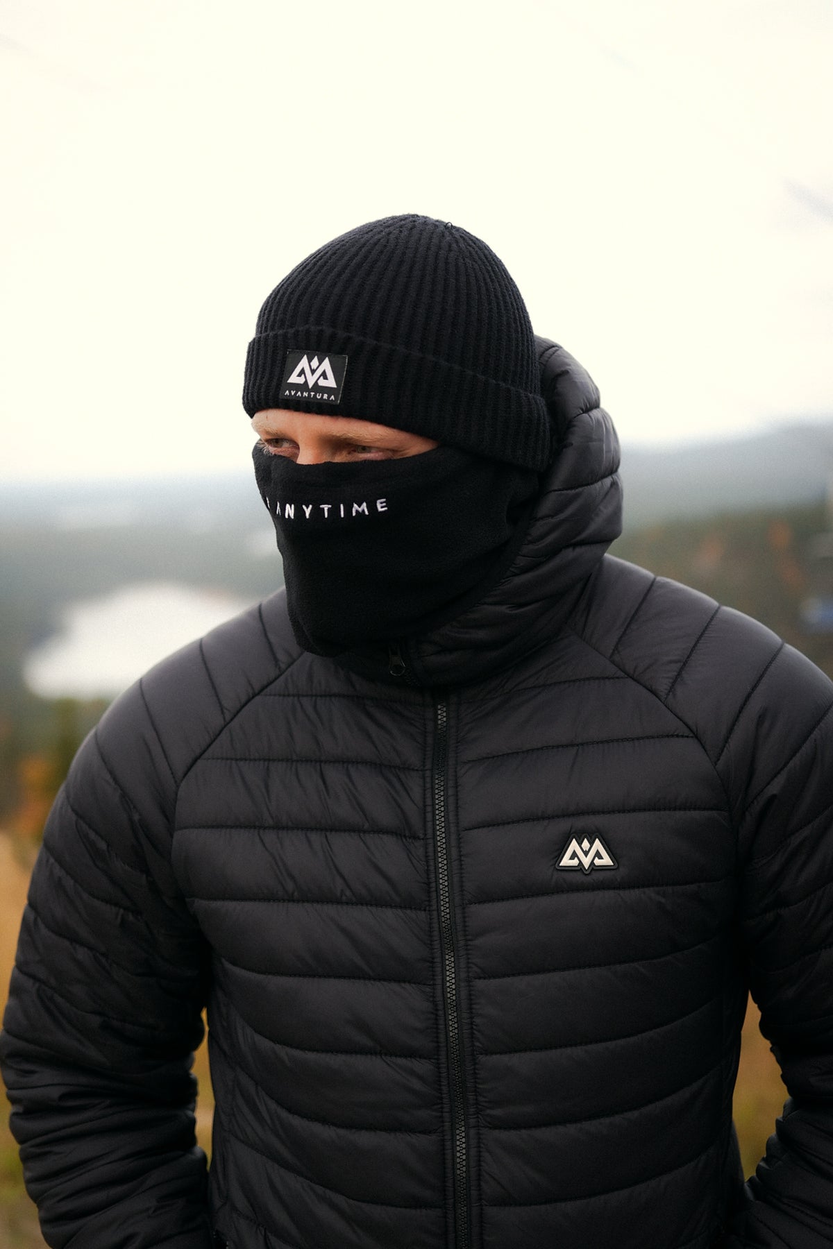 Side view of black ribbed beanie with folded cuff and logo patch