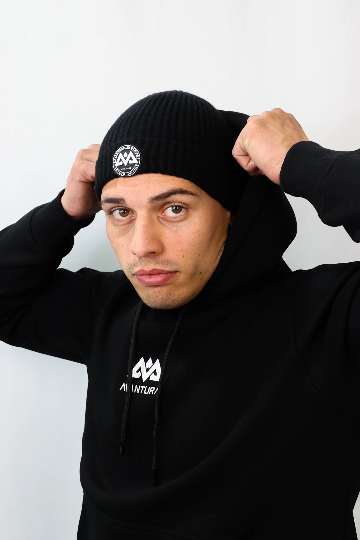 Avantura black beanie showing circular rubber patch logo on front