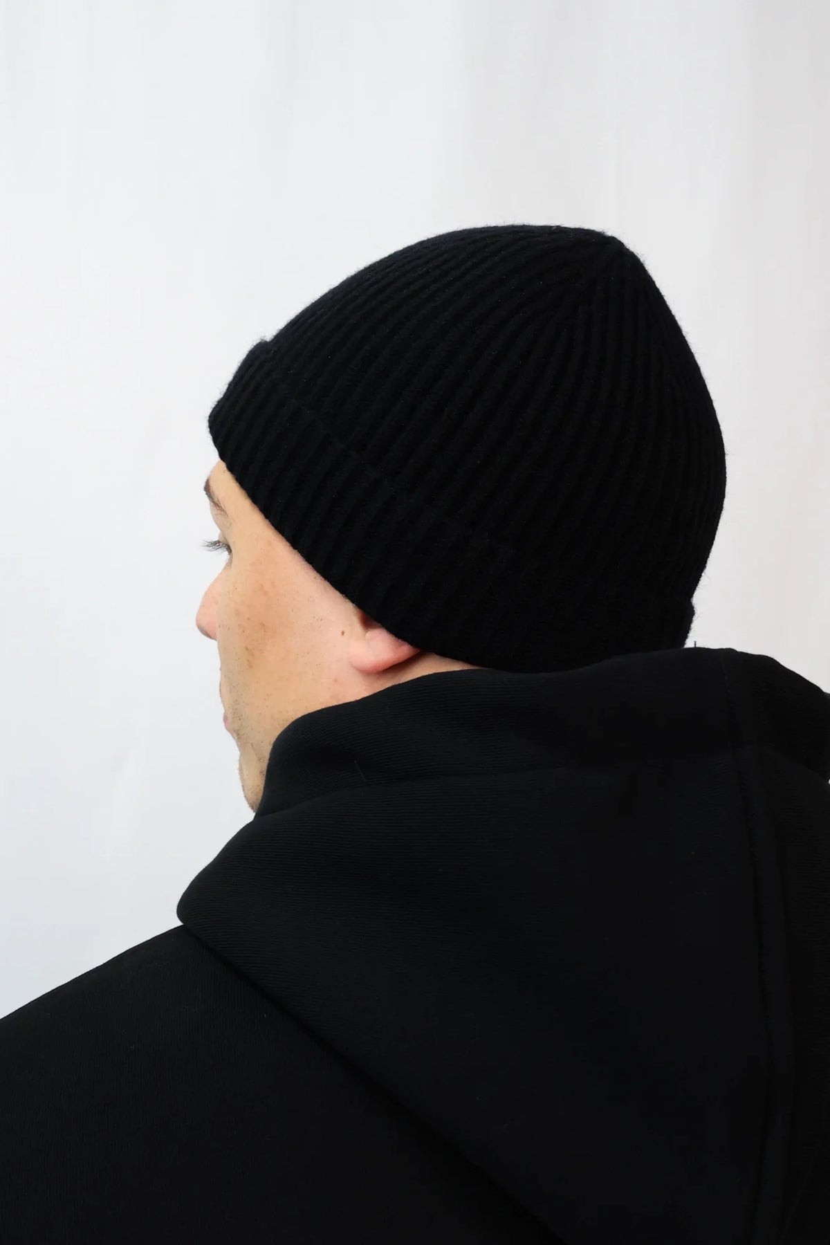 Black ribbed knit beanie with folded cuff worn by model