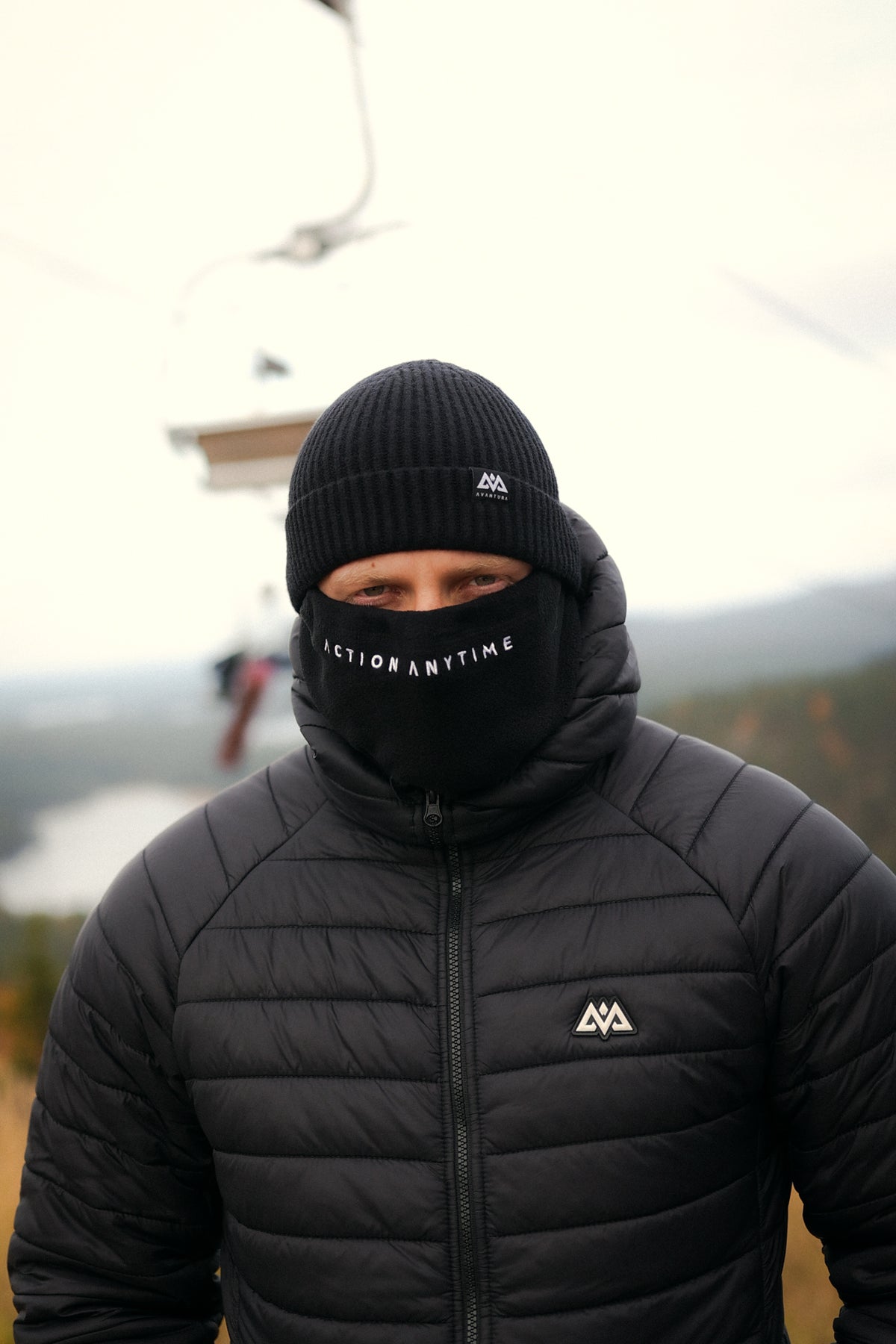 Schwarze Beanie im Winter-Outfit mit Gesichtsmaske und Daunenjacke