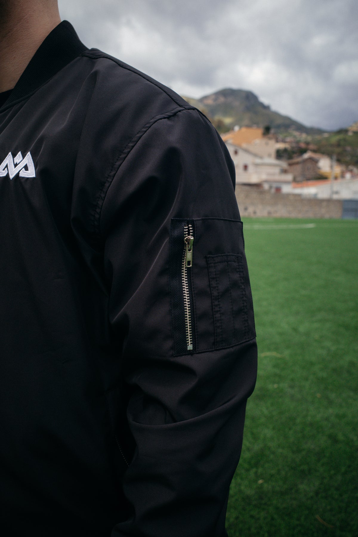 Side view of black bomber jacket with arm pocket