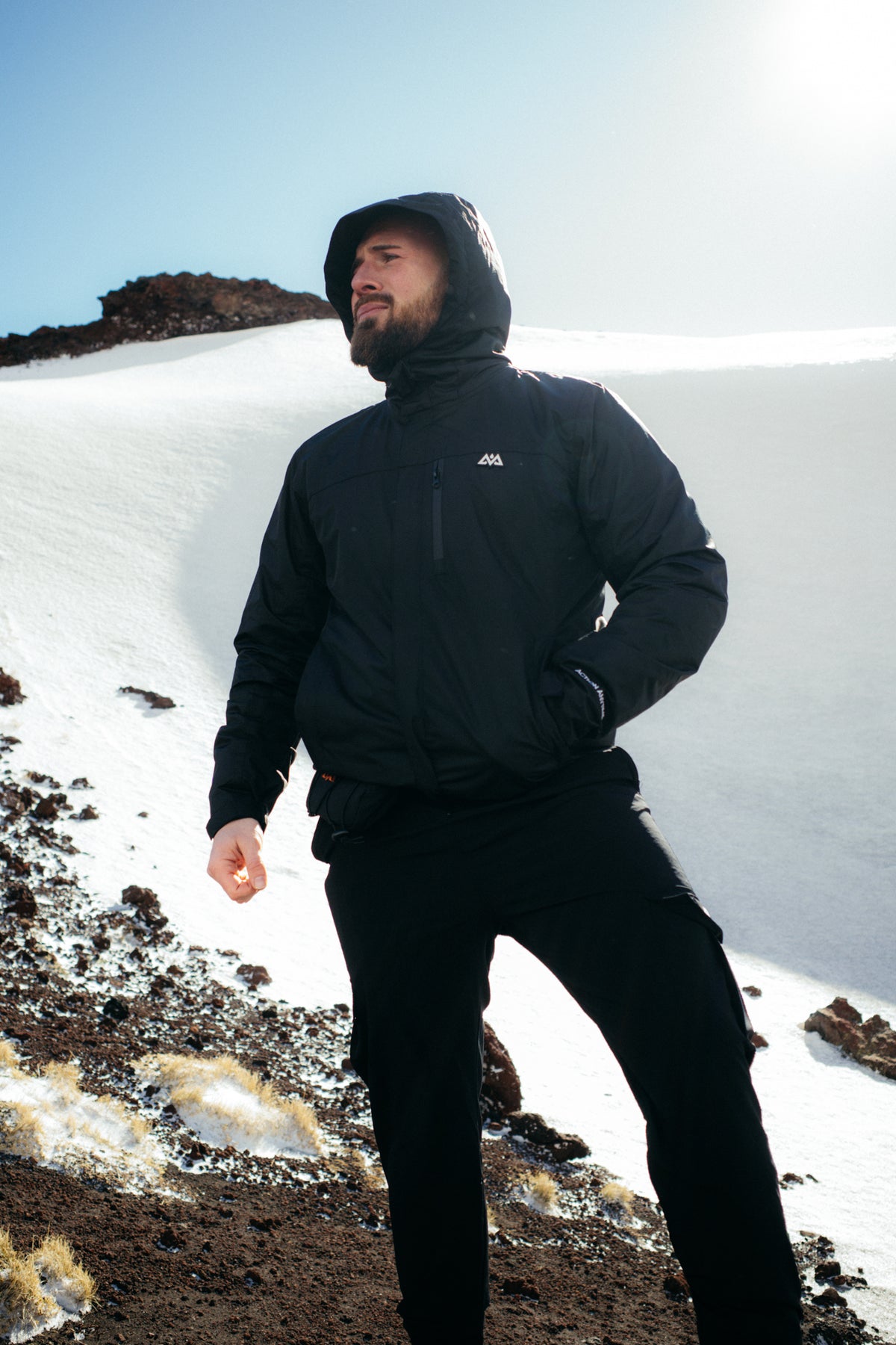 Mann in schwarzer Cargohose und Kapuzenjacke bei Sonne