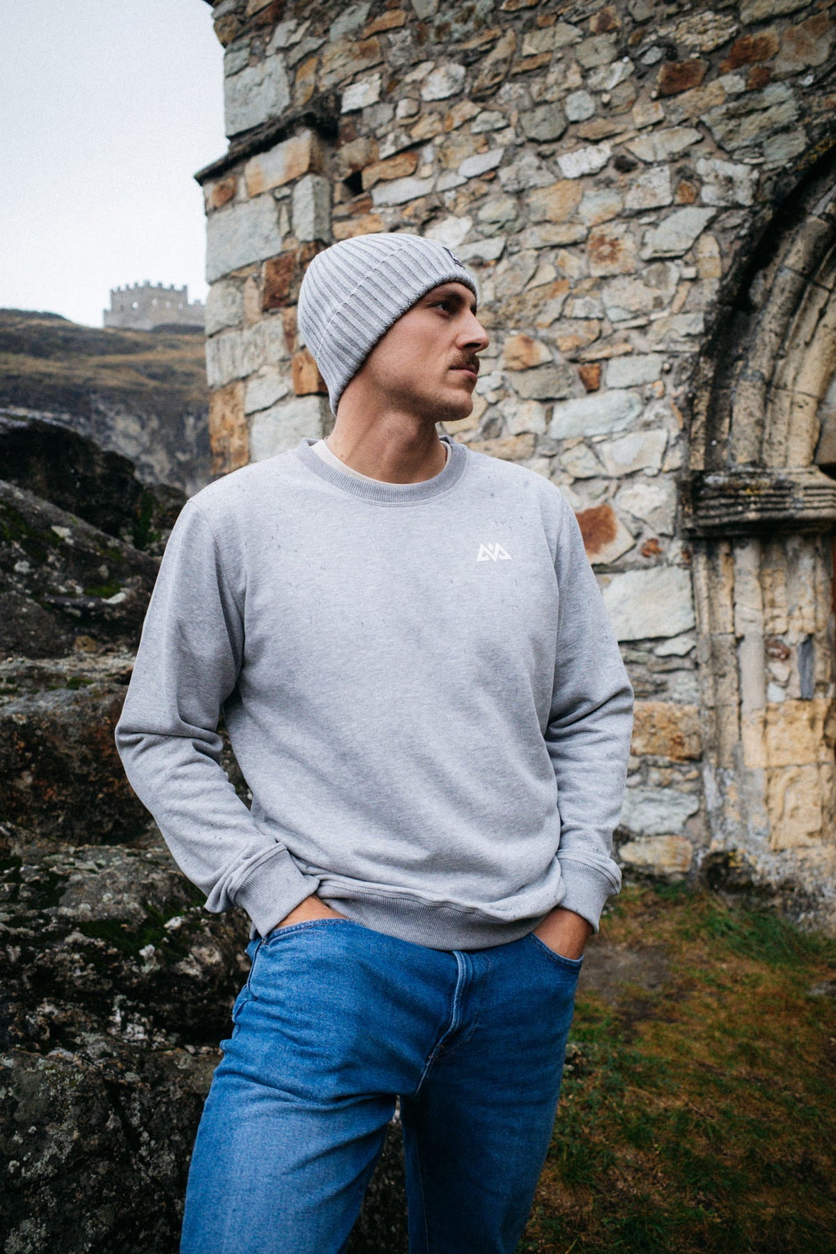 Grauer Crewneck Pullover mit weißem Brustlogo und passender Strickmütze