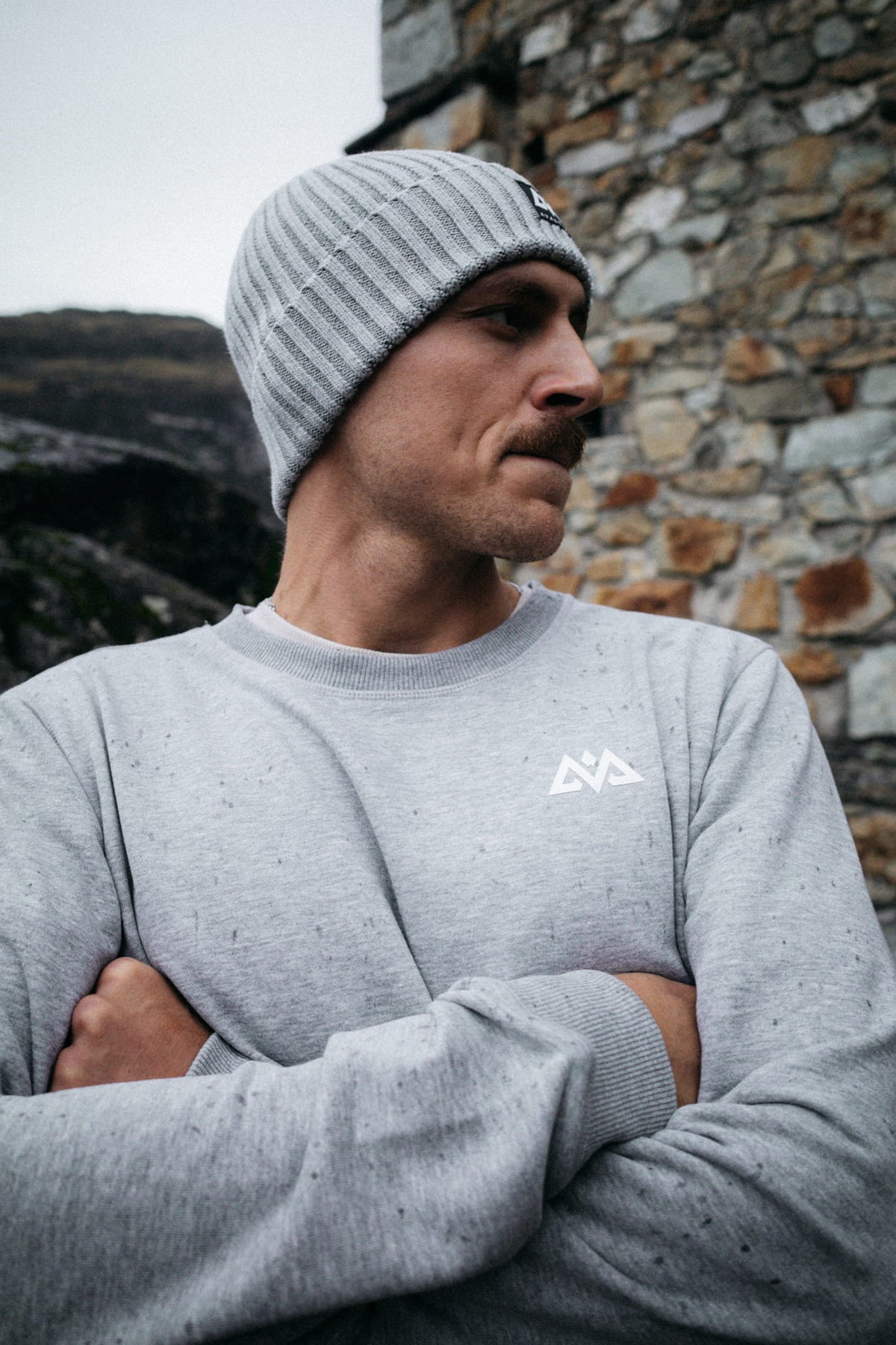 Graues Crewneck Sweatshirt mit geometrischem Logo und Mütze getragen