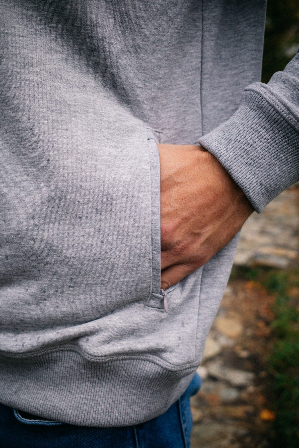 Nahaufnahme der Seitentasche mit Reißverschluss am grauen AVA Sweatshirt
