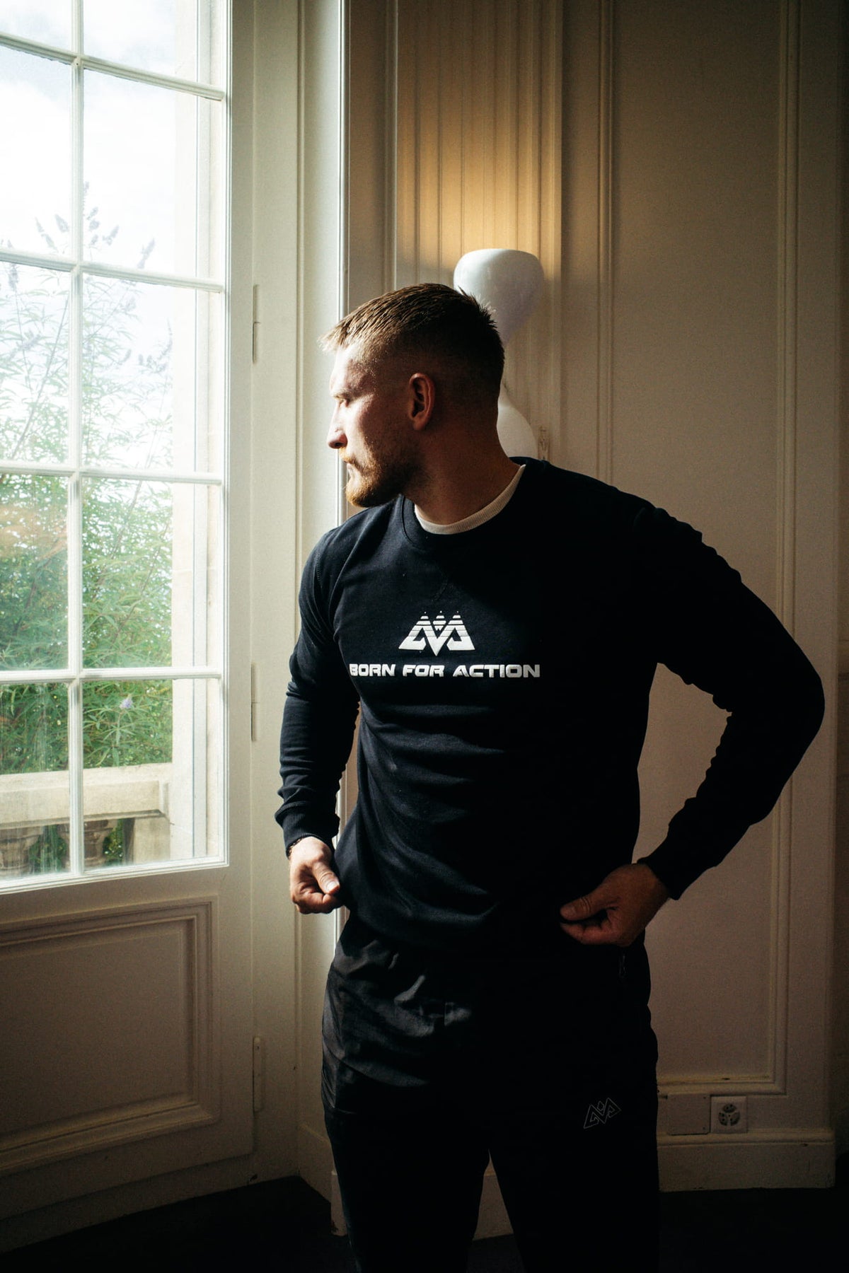Mann trägt schwarzen Crewneck Sweatshirt mit BORN FOR ACTION Aufdruck