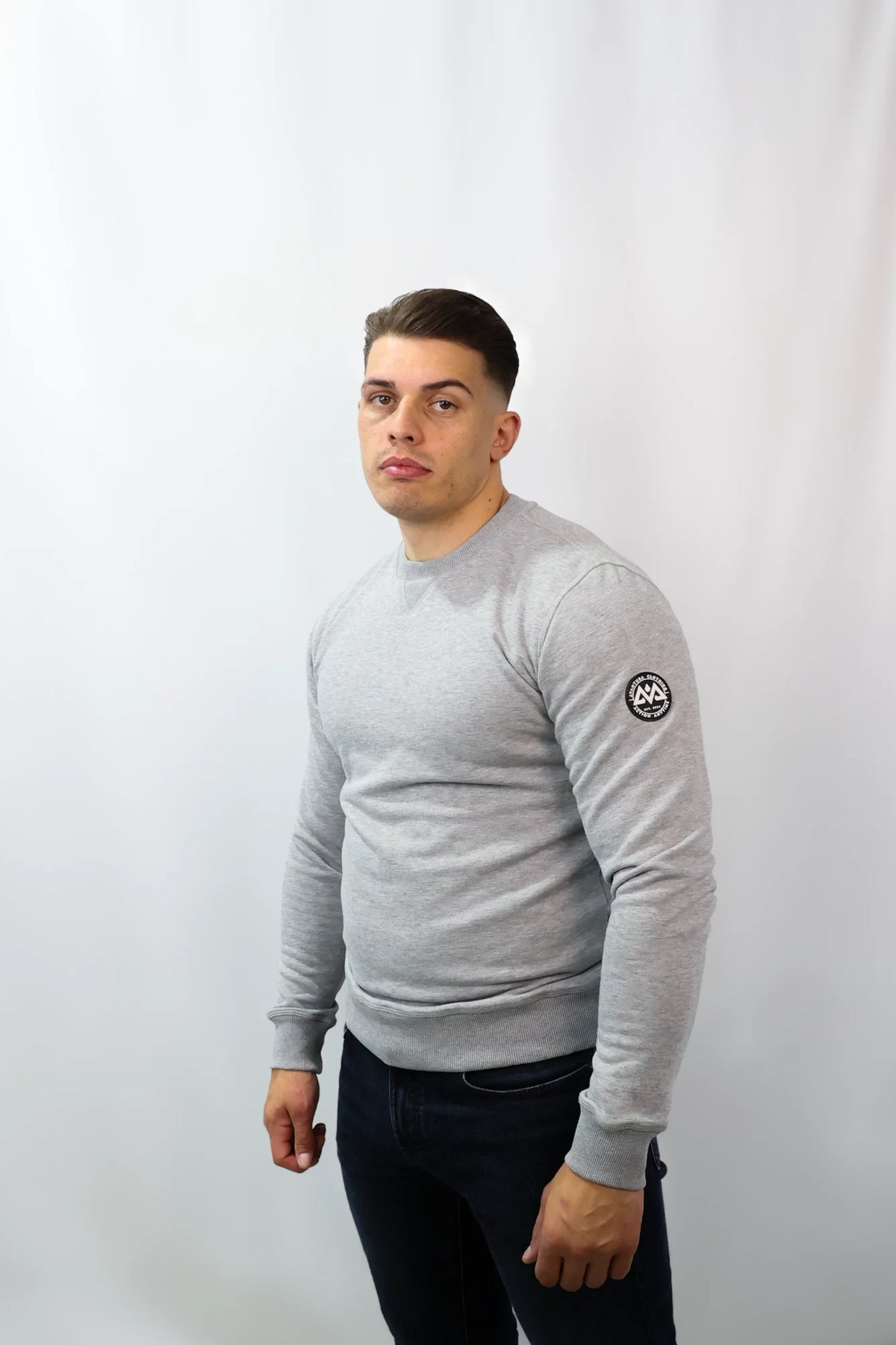 Men's light grey crewneck sweater styled with dark jeans for casual fit