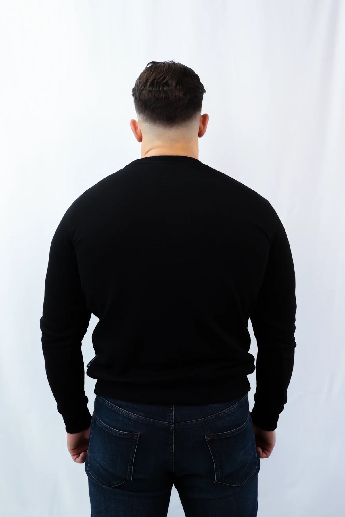 Back view of plain black crewneck sweater on male model