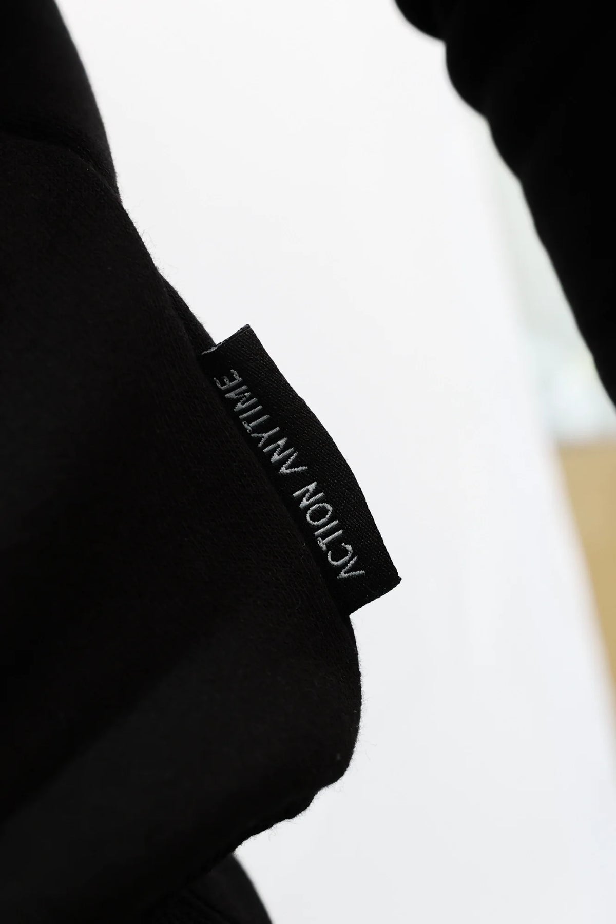 Inner neckline label of black crewneck sweater showing brand text