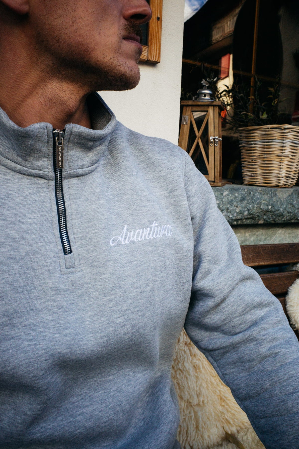 Close-up of gray half-zip sweater with silver zipper and embroidery