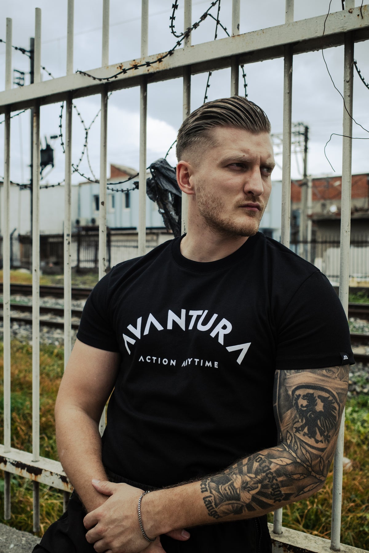 Black short-sleeve T-shirt with prominent white arched 'AVANTURA' and 'ACTION ANYTIME' print