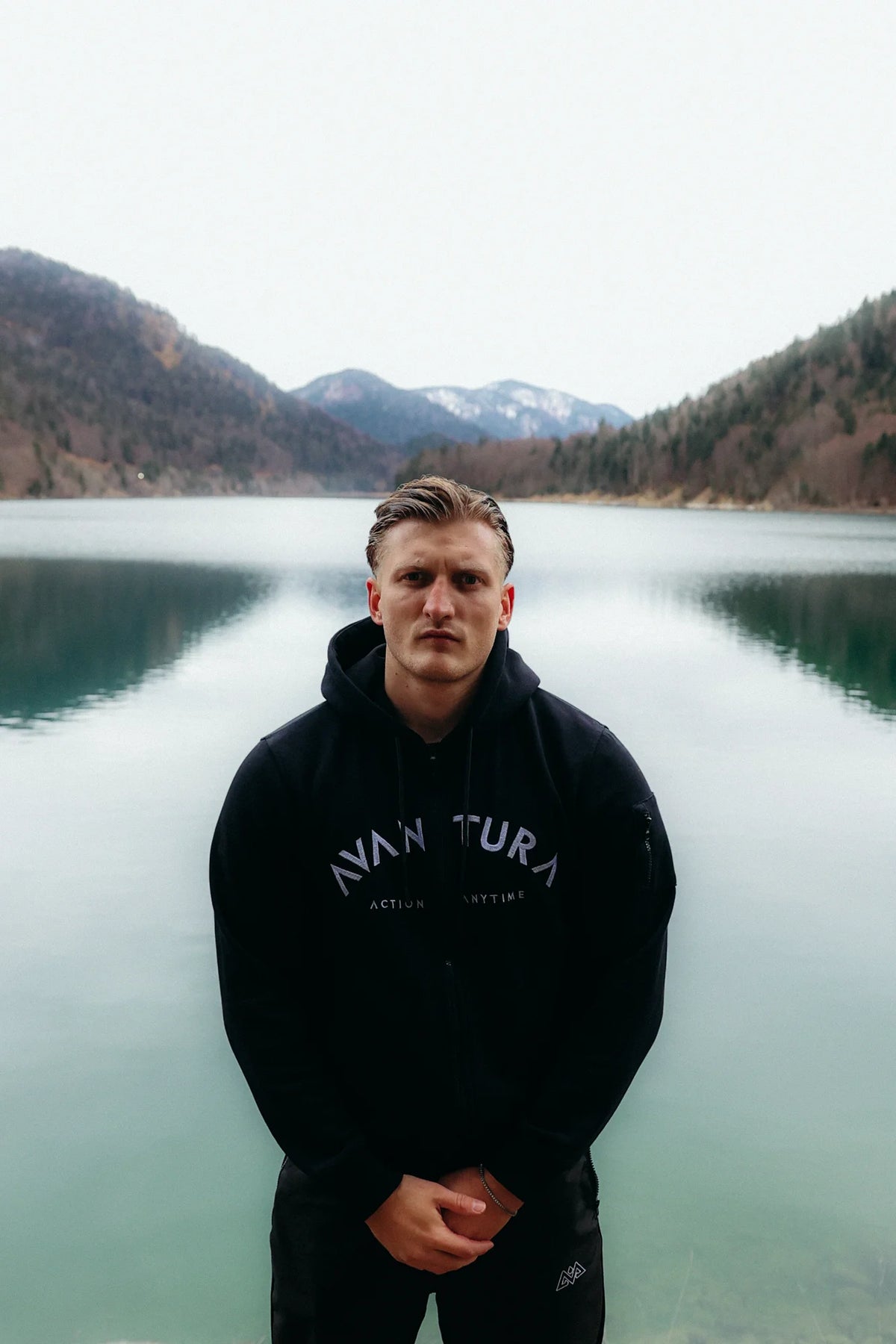 Front view of black zip-up hoodie with grey arched lettering