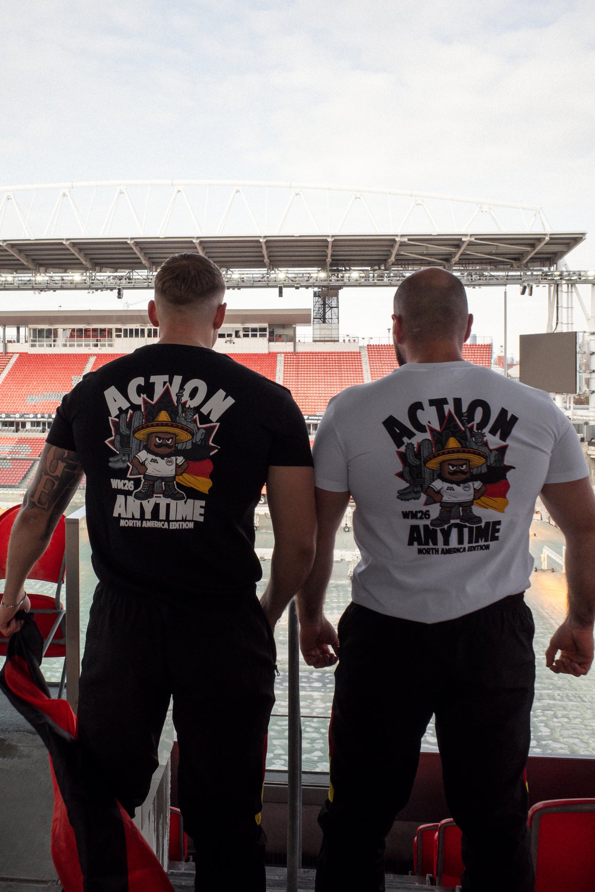Two men in stadium wearing black and white T-shirts with matching back graphics