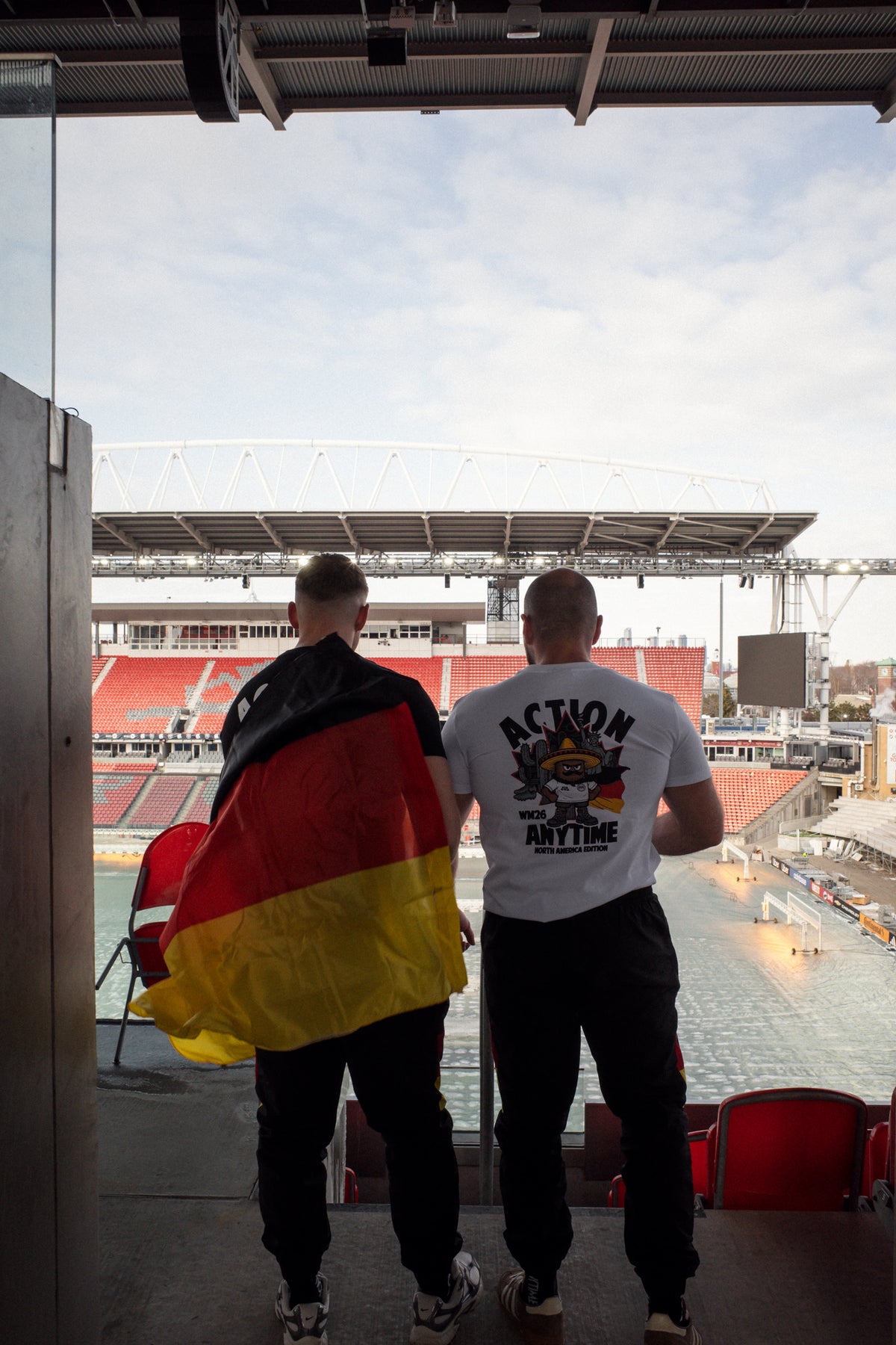 Weiße T-Shirts mit großem Rückenaufdruck vor Fußballstadion-Hintergrund
