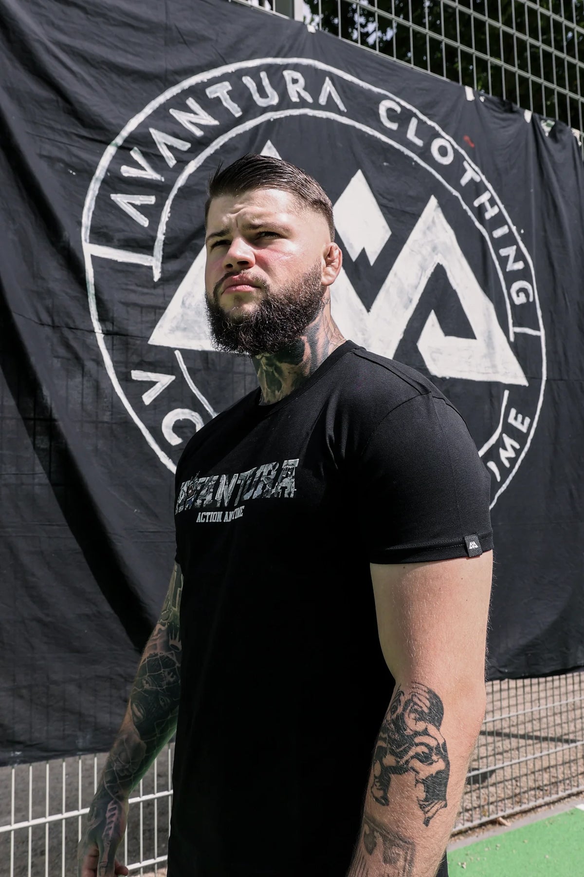 Side profile of black T-shirt showing woven sleeve label and chest graphic detail
