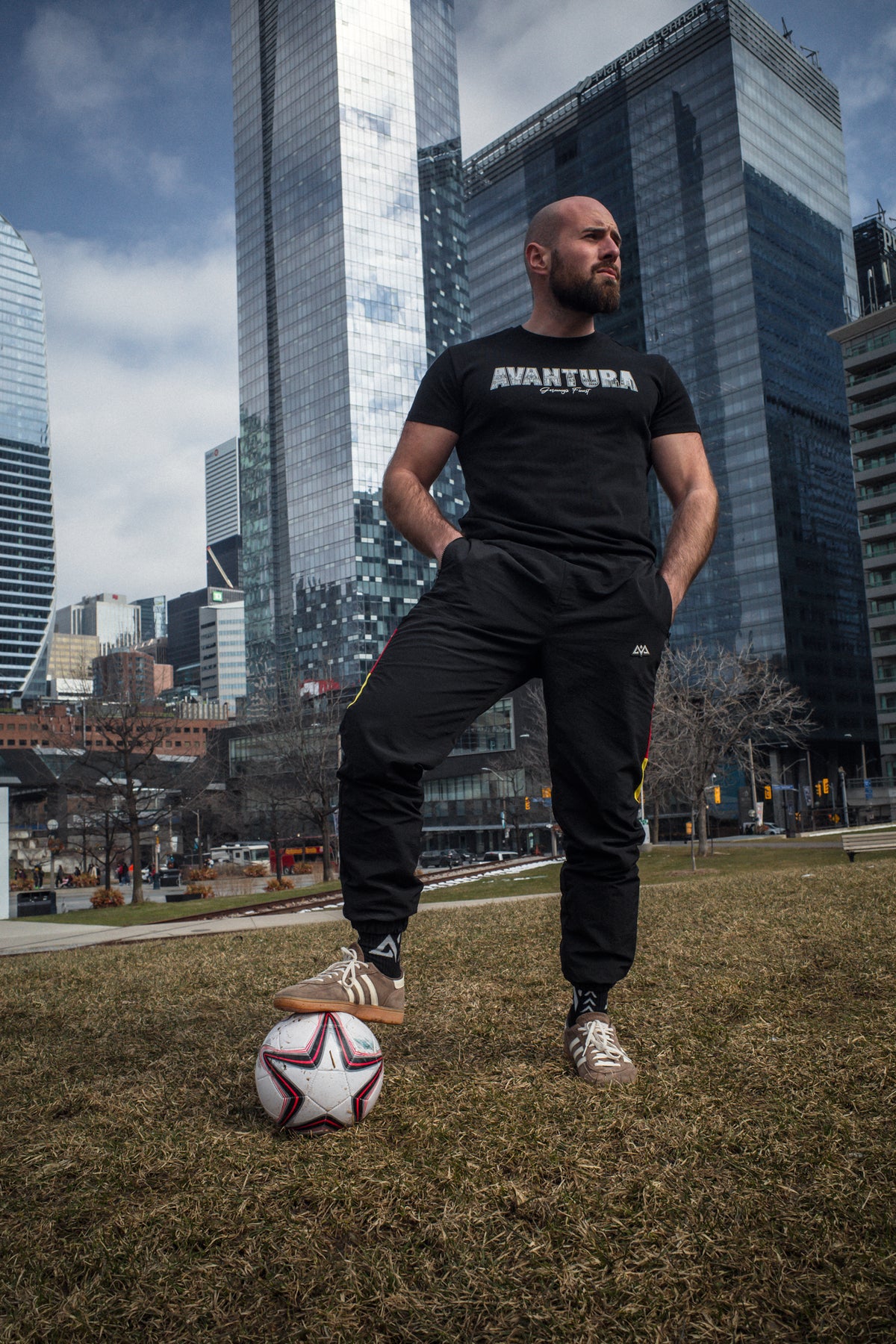 Avantura T-Shirt Schwarz auf Wiese mit Fußball und Skyline