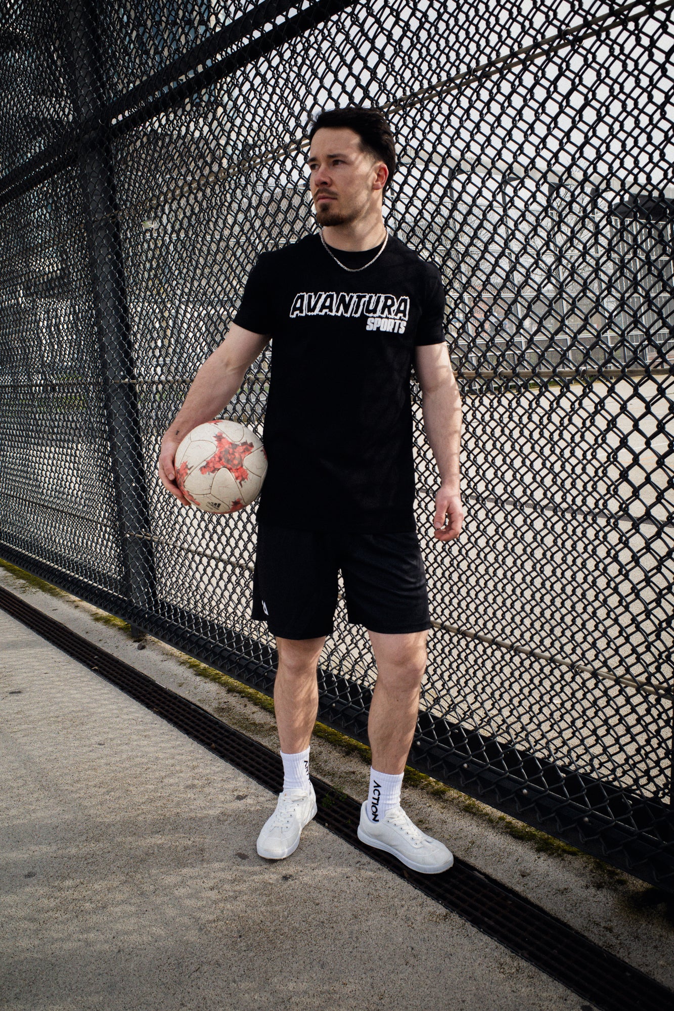 Man holding soccer ball wearing black Avantaura Sports printed T-shirt