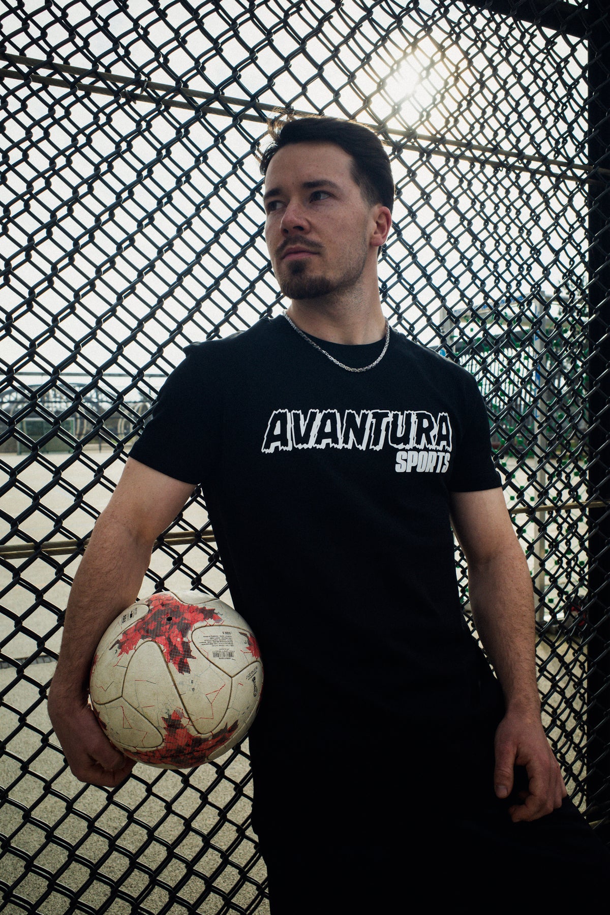 Close-up of black crew neck T-shirt with centered white 'Avantaura Sports' text