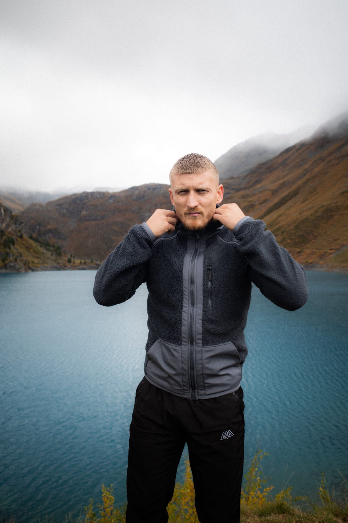 Graue Fleecejacke mit hellgrauem Brustpanel und hochgestelltem Kragen am See