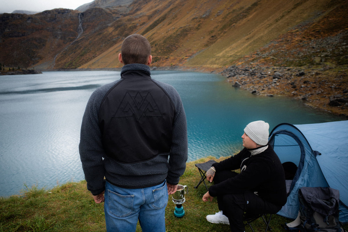 Fleecejacke mit großem Rückendesign vor See und Zelt im Hintergrund