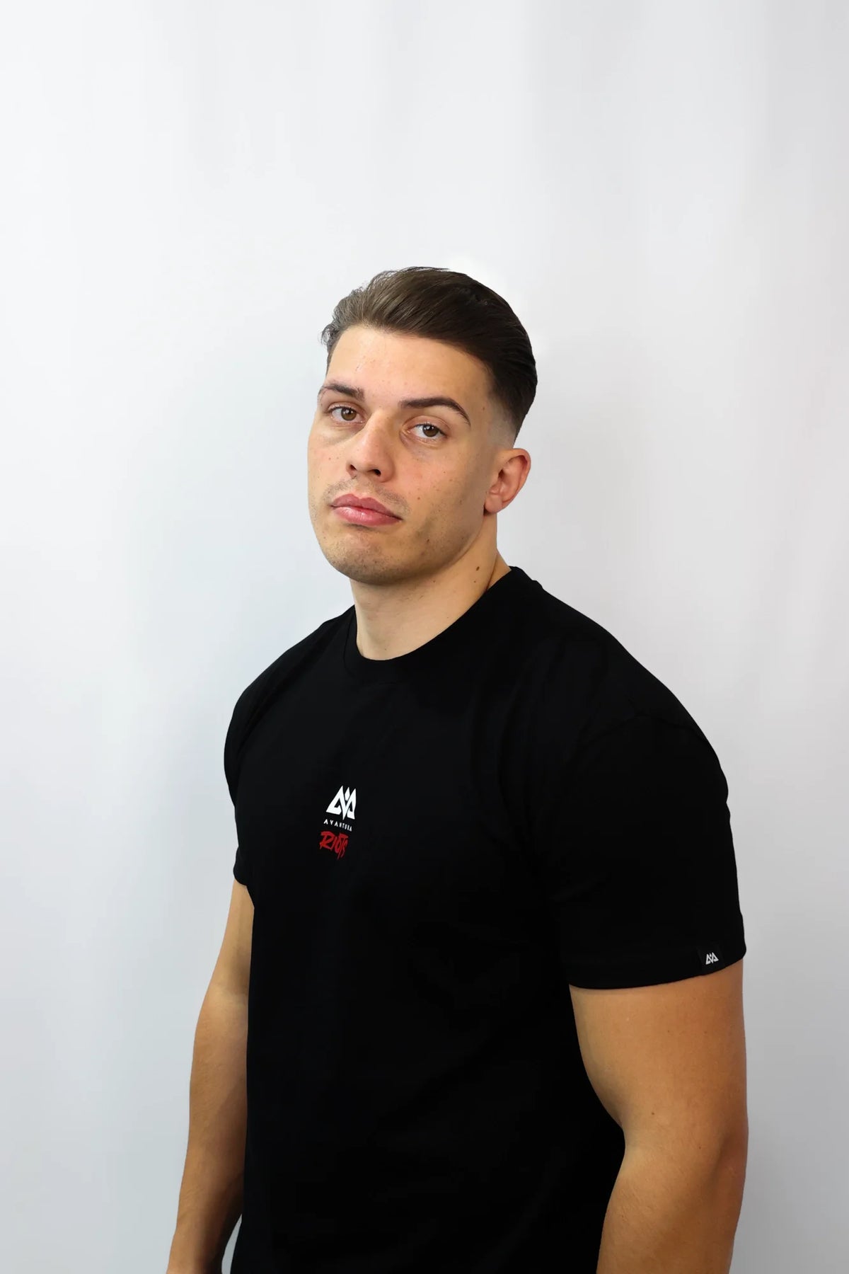 Man wearing black crew-neck t-shirt with small chest logo and woven sleeve label