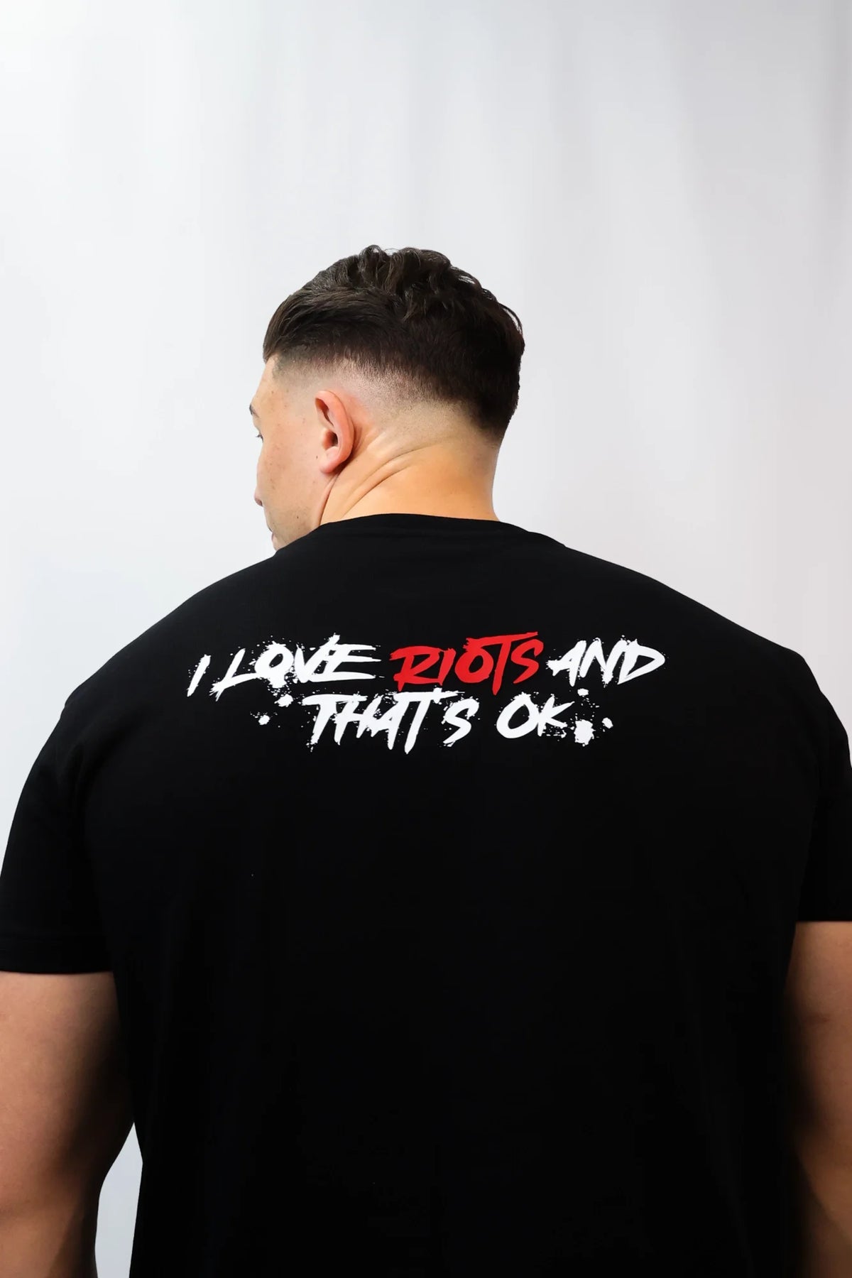 Back view of black t-shirt with large 'I LOVE RIOTS' graphic print in white and red