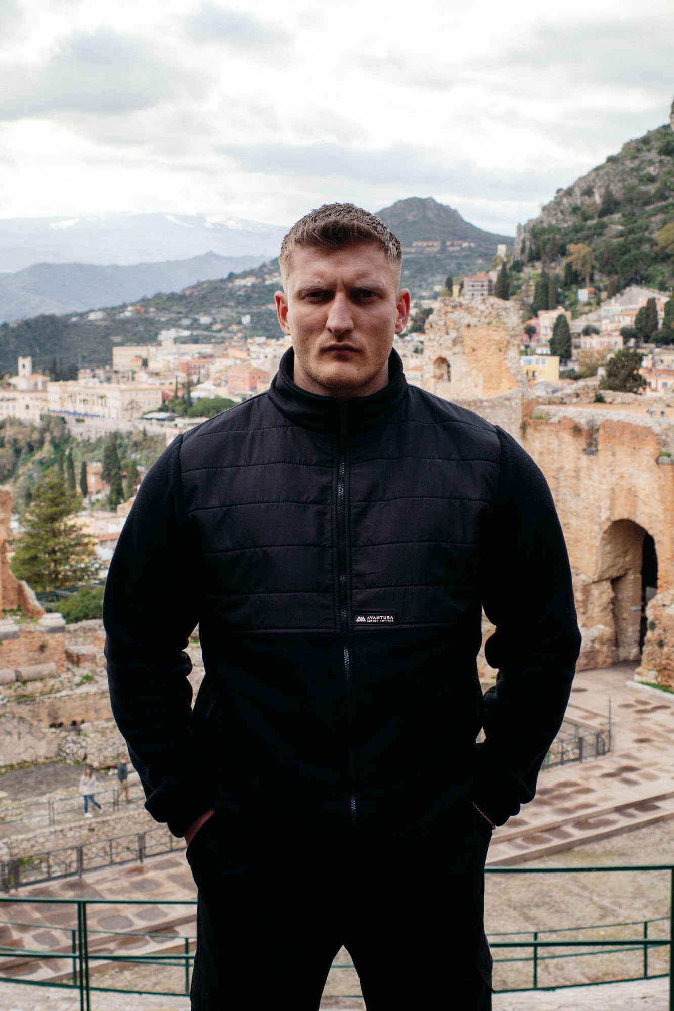 Full-zip black fleece jacket with quilted torso and smooth sleeves, hands in pockets
