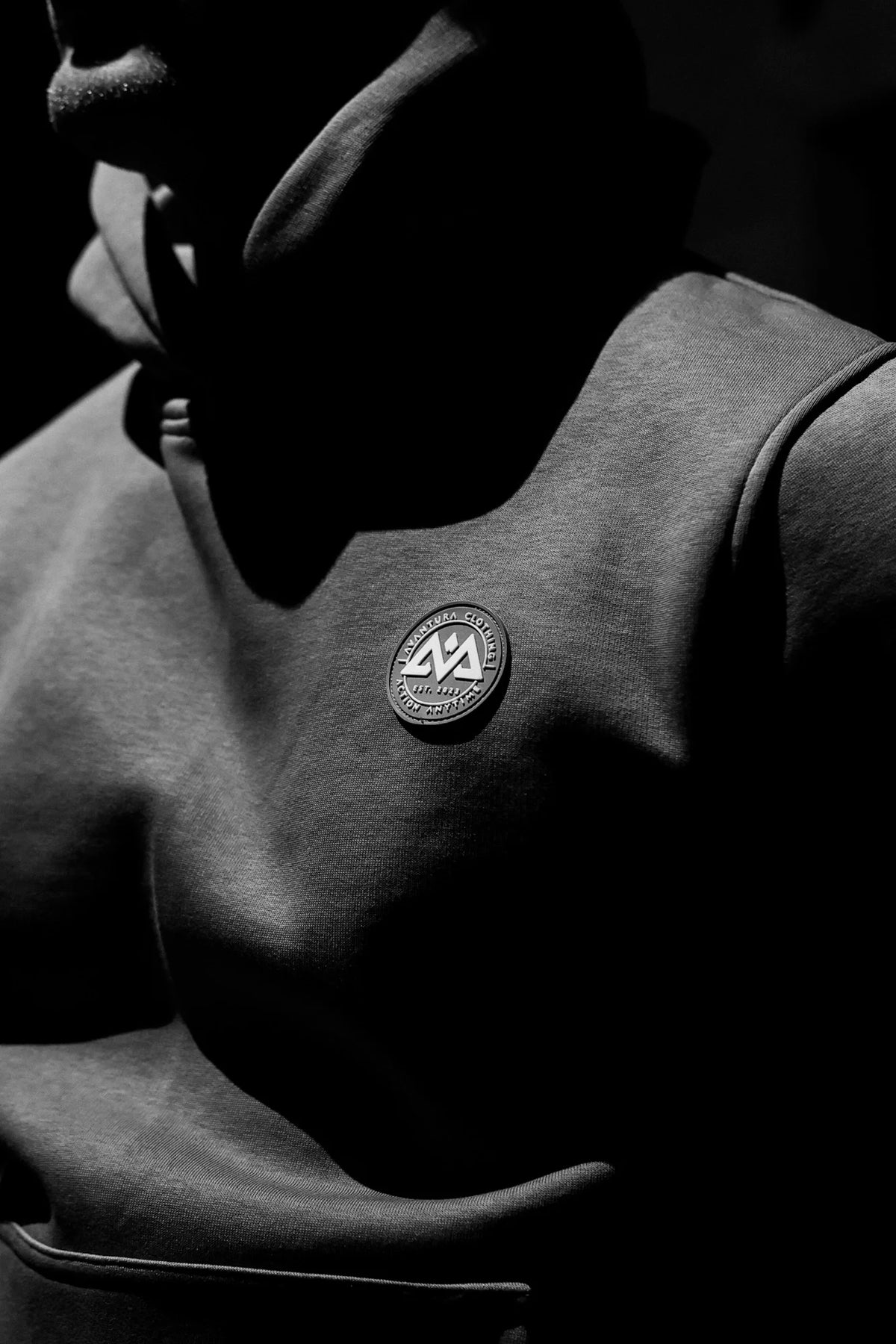 Close-up of AVANTURA CLOTHING logo patch on gray hoodie