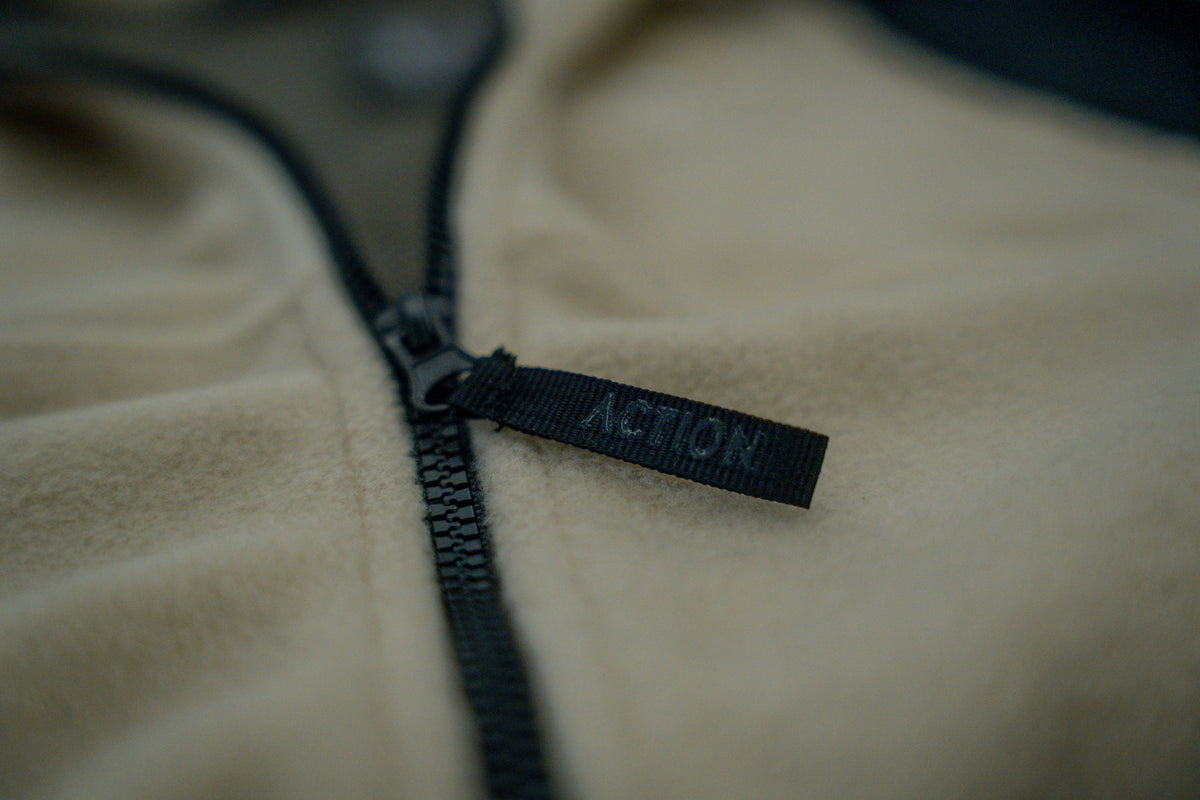 Macro detail of black zipper and soft napped texture on beige fleece