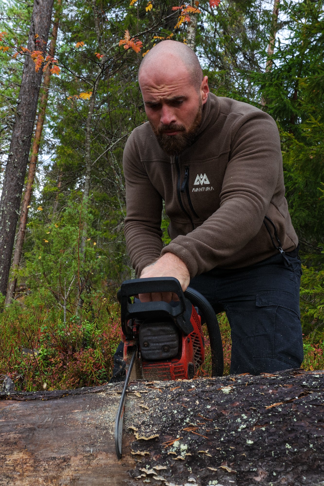 Man using chainsaw in brown Avantura fleece jacket for outdoor work